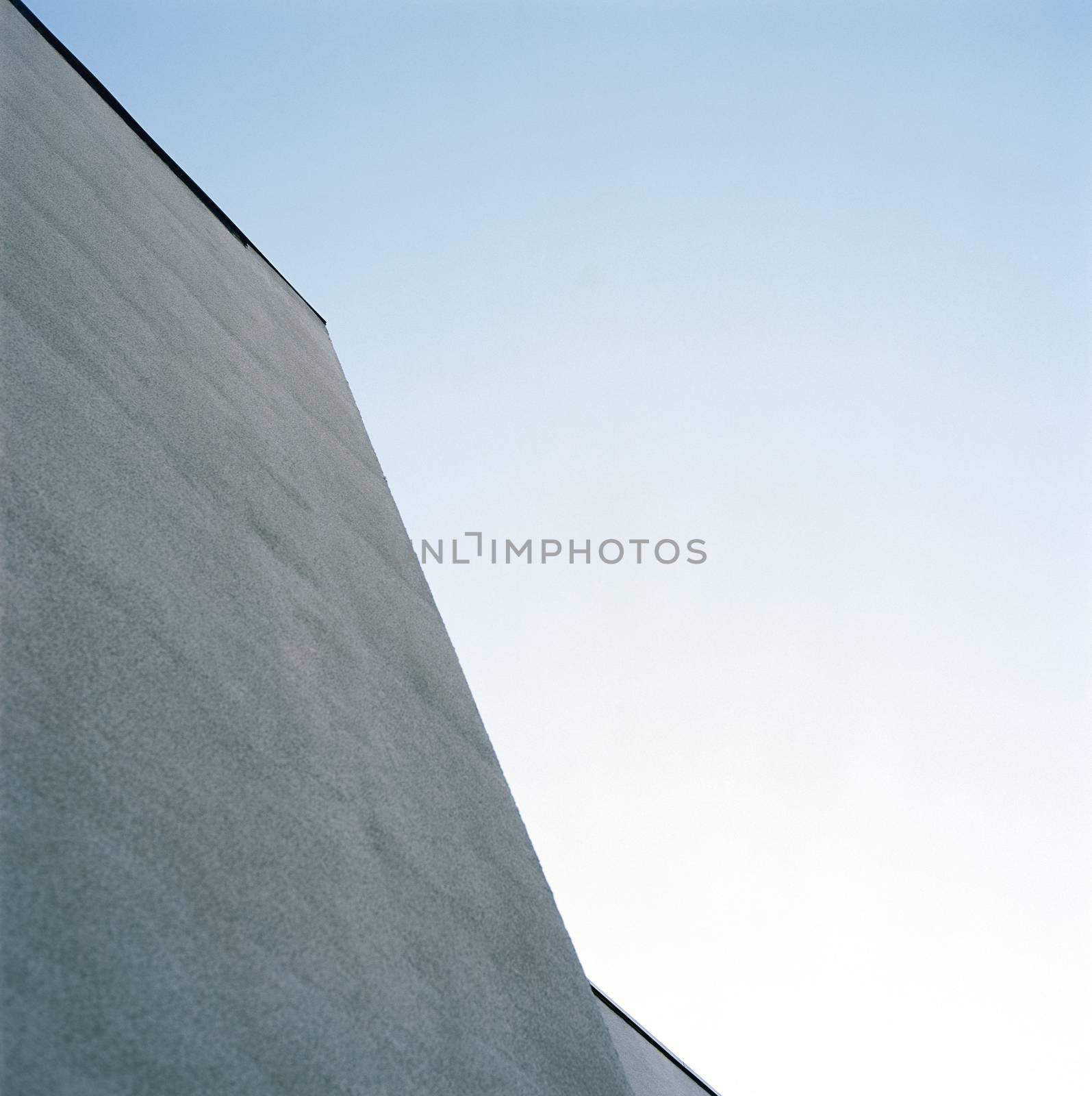 Looking up at the modern architecture of a monochromatic exterior wall 