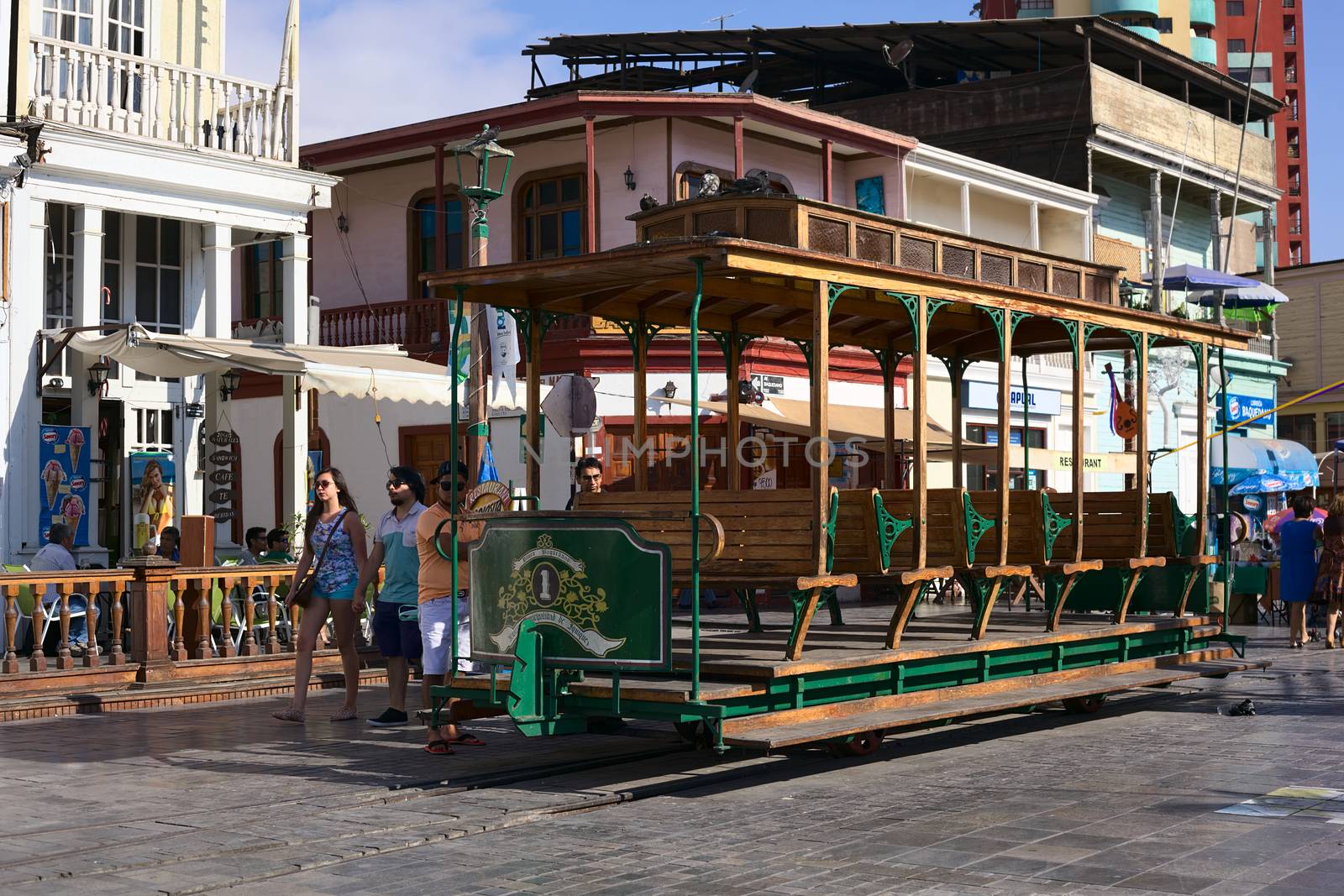 IQUIQUE, CHILE - JANUARY 22, 2015: Unidentified people around an old open tram waggon with wooden seats on Plaza Prat main square along Baquedano avenue on January 22, 2015 in Iquique, Chile