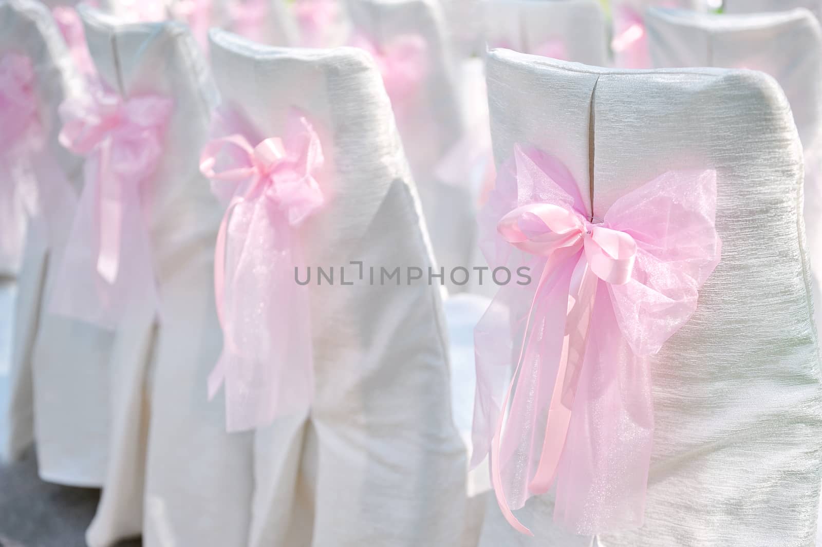 Decoration on wedding chairs pink bow in summer park 