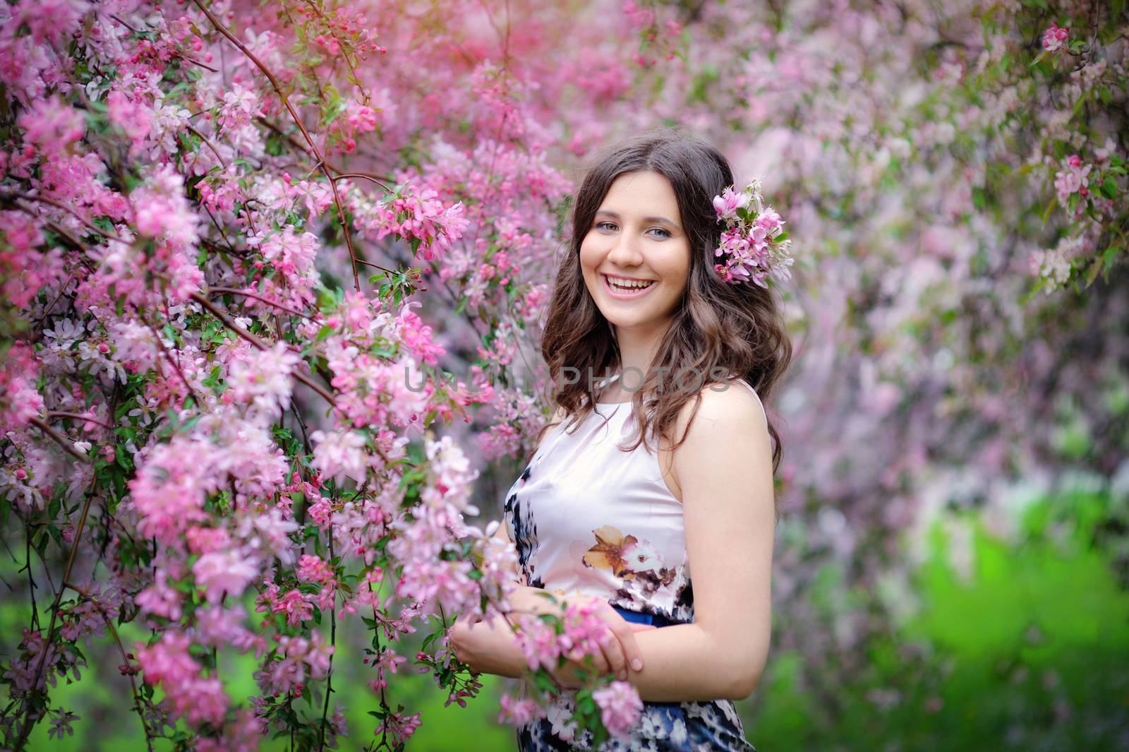 Beautiful woman walking in blossoming spring garden