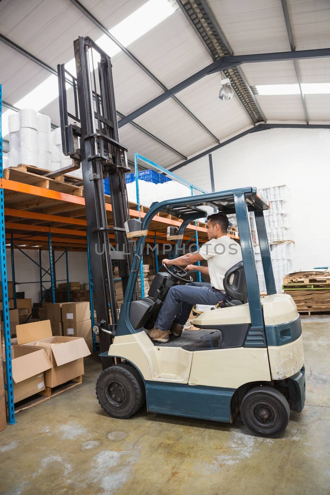 Forklift machine in a large warehouse by Wavebreakmedia
