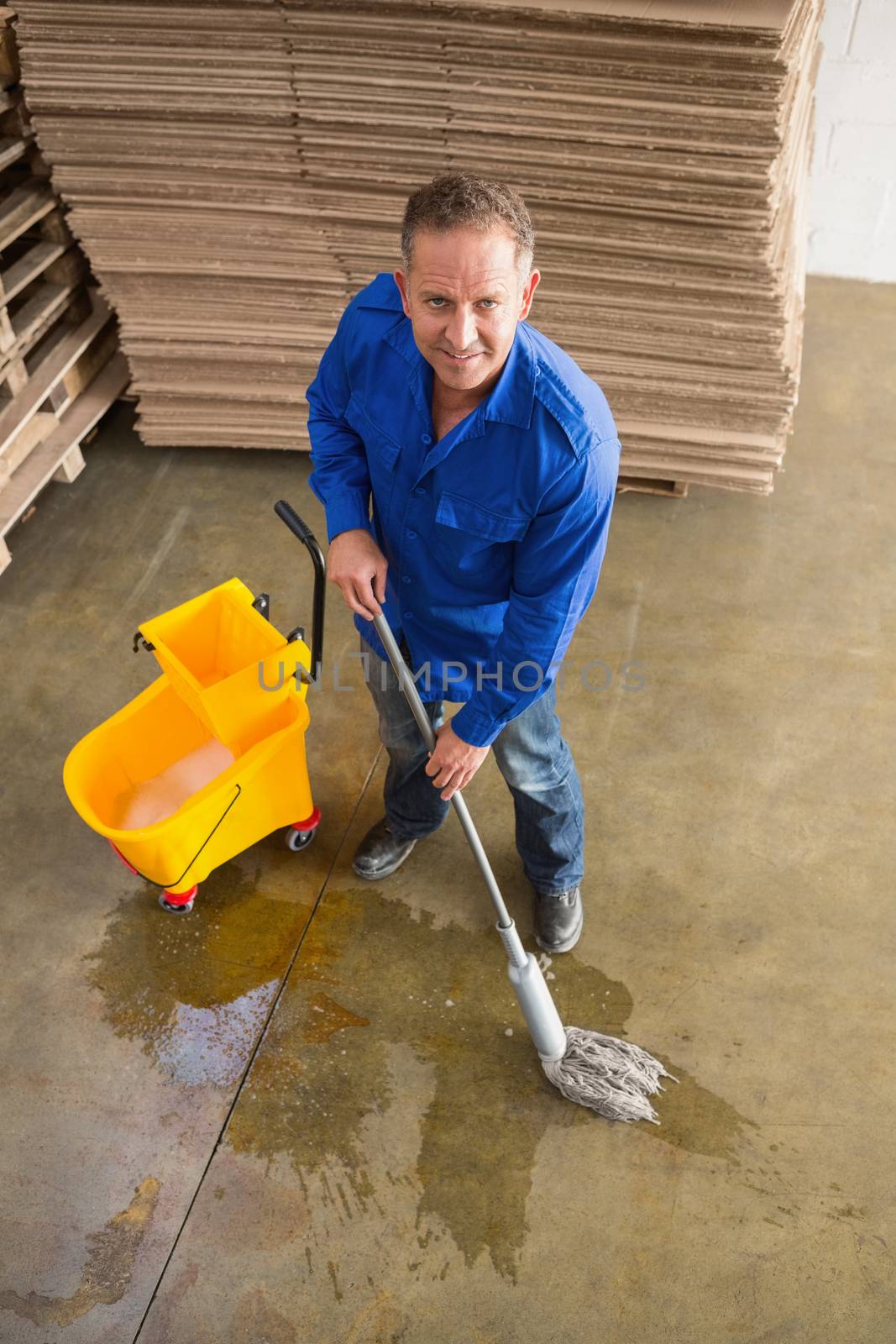 Portrait of smiling man moping warehouse floor