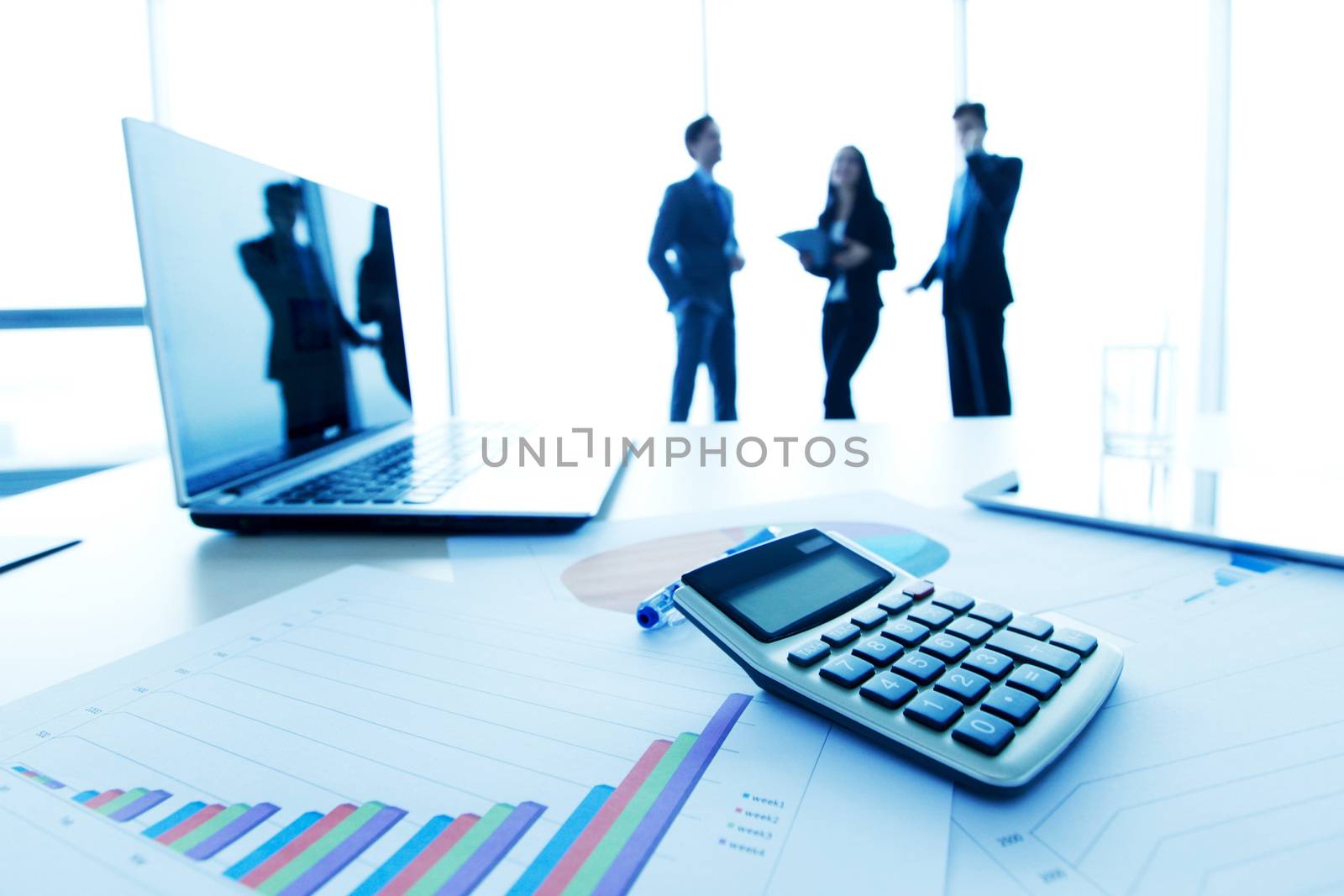desk with laptop and finance report with business people in background