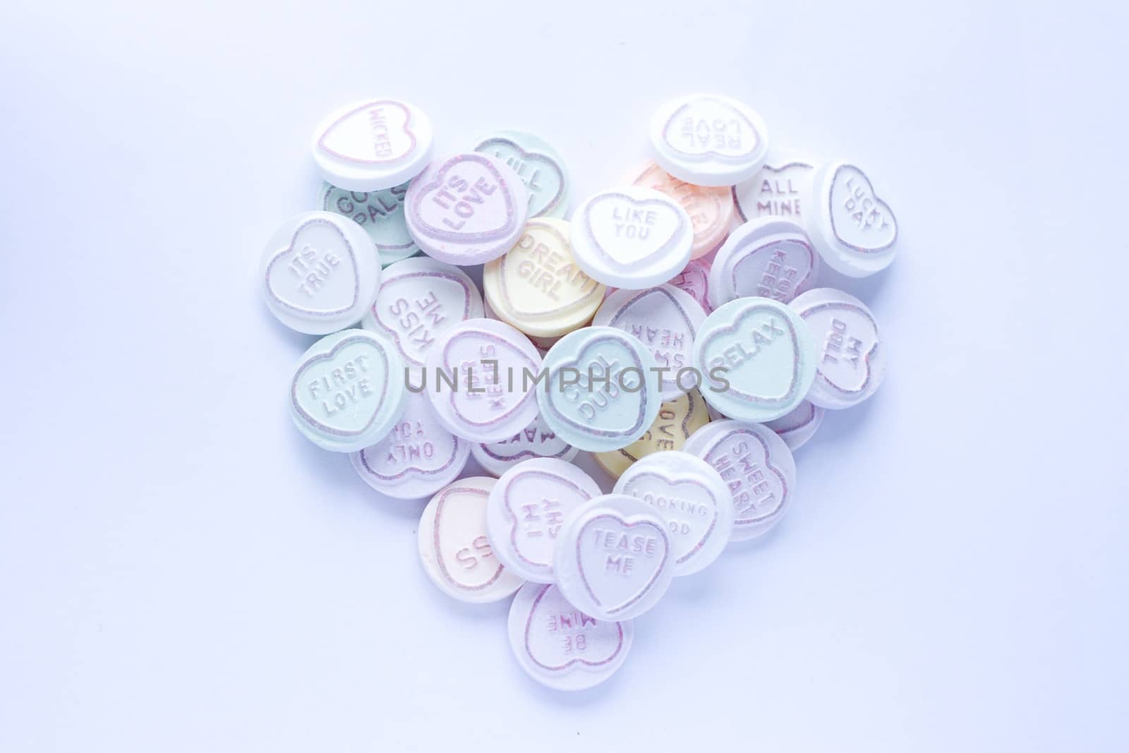 Sweets with text in a heart shape against a white background. This type of confectionary is produced by Swizzles Matlow in the UK.