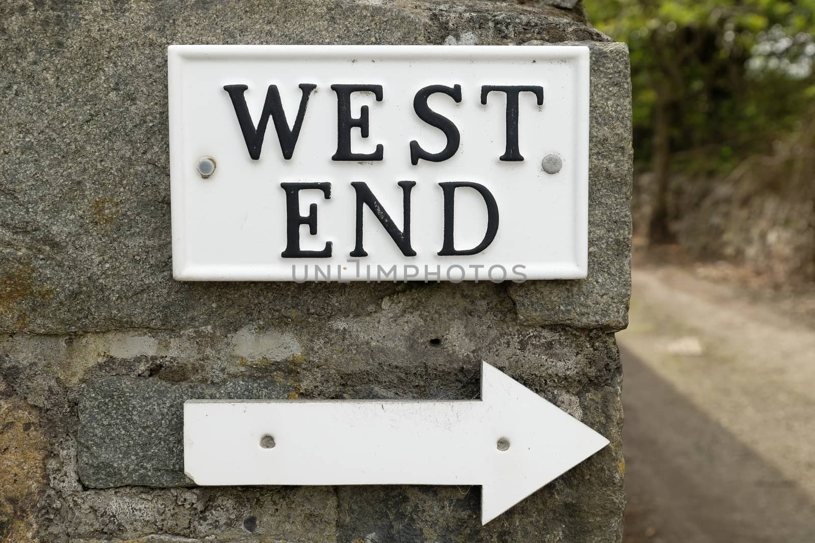 A white rectangular plaque with the words "WEST END" painted in black with a directional arrow underneath.