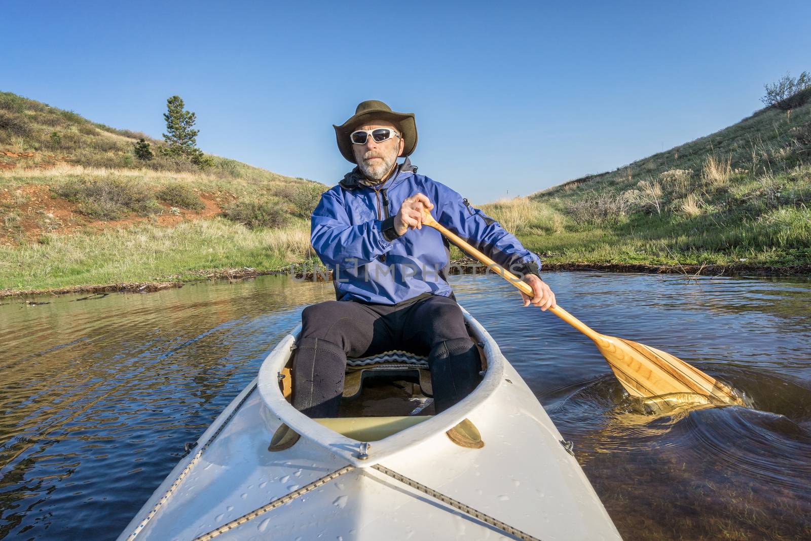 senior paddler in a decked expedition canoe on Horsetooth Reservoir, Fort Collins, Colorado, springtime scenery