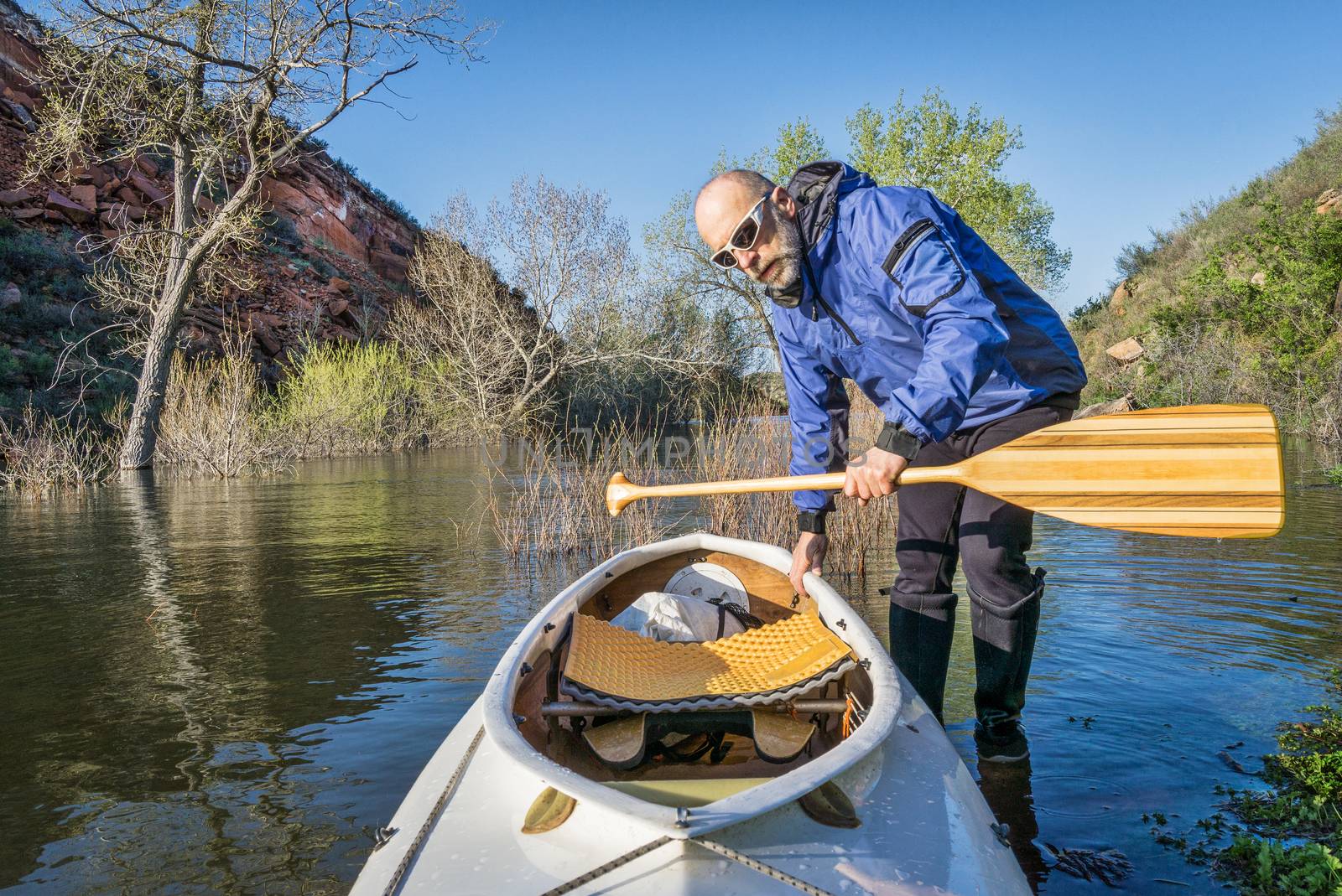 senior paddler and decked expedition canoe on the shore of Horsetooth Reservoir, Fort Collins, Colorado, springtime scenery