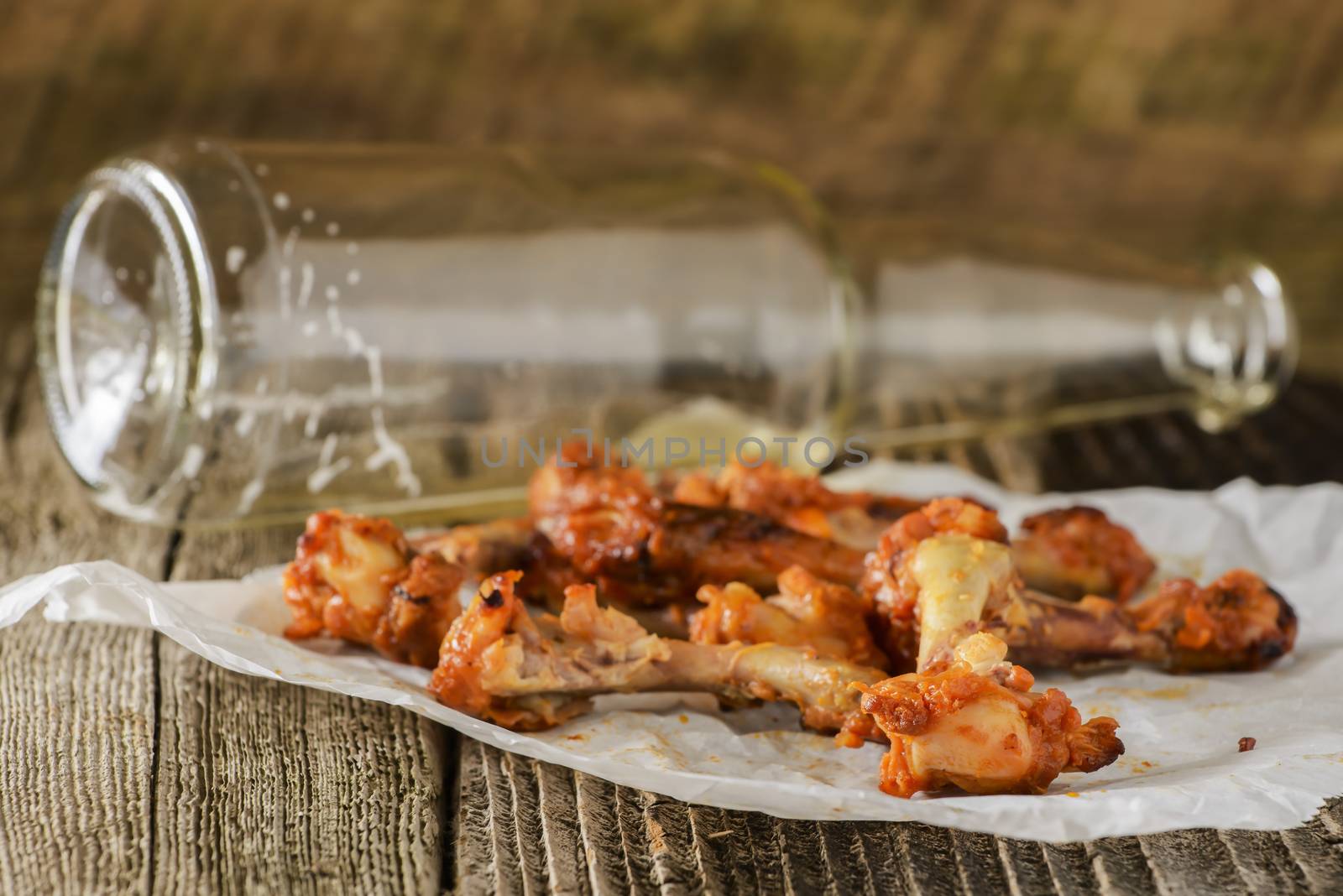 Pile of eaten barbecued chicken wings on a rustic wood background.