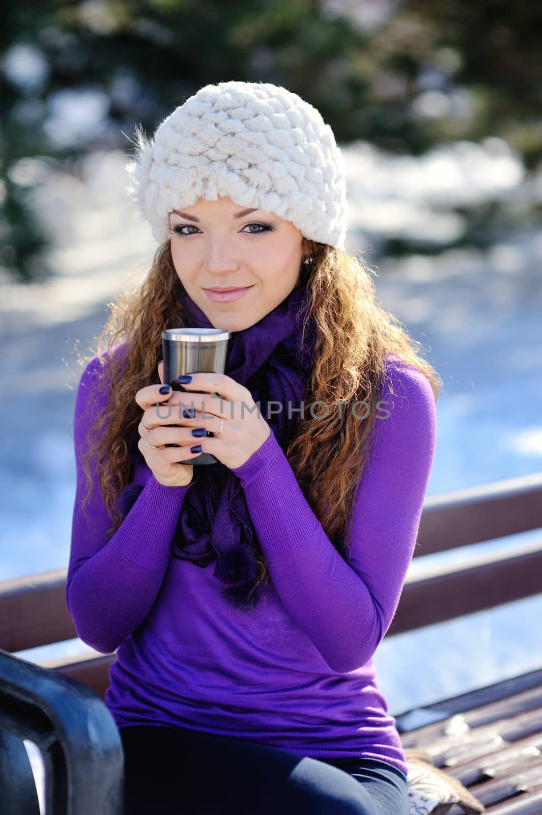 beautiful girl on a bench with a cup of coffee in the winter.