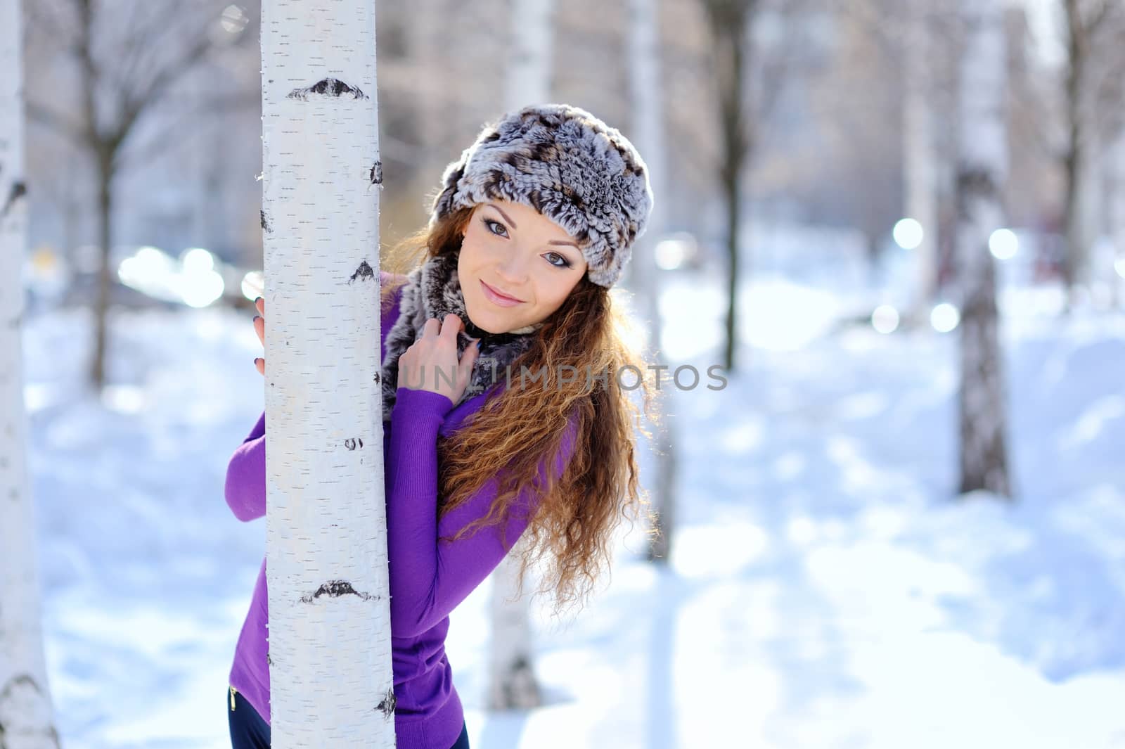 beautiful girl standing near birch tree in winter park.