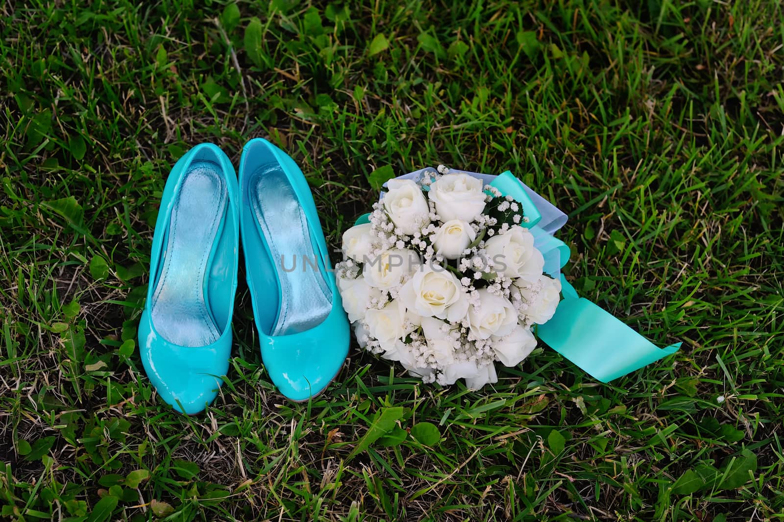 bridal bouquet and turquoise shoes on green grass.