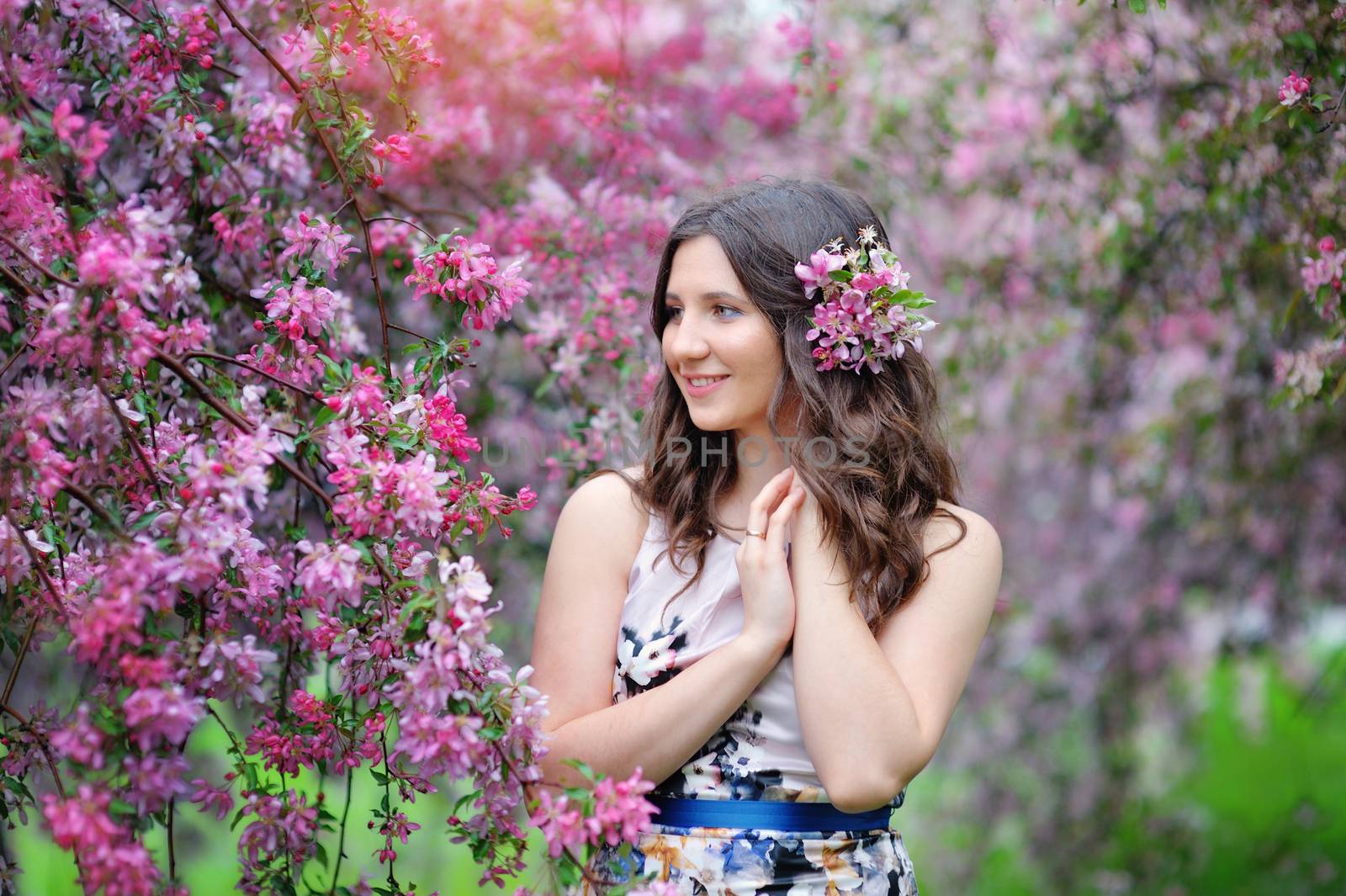 beautiful smiling woman and pink flowers outside in spring.