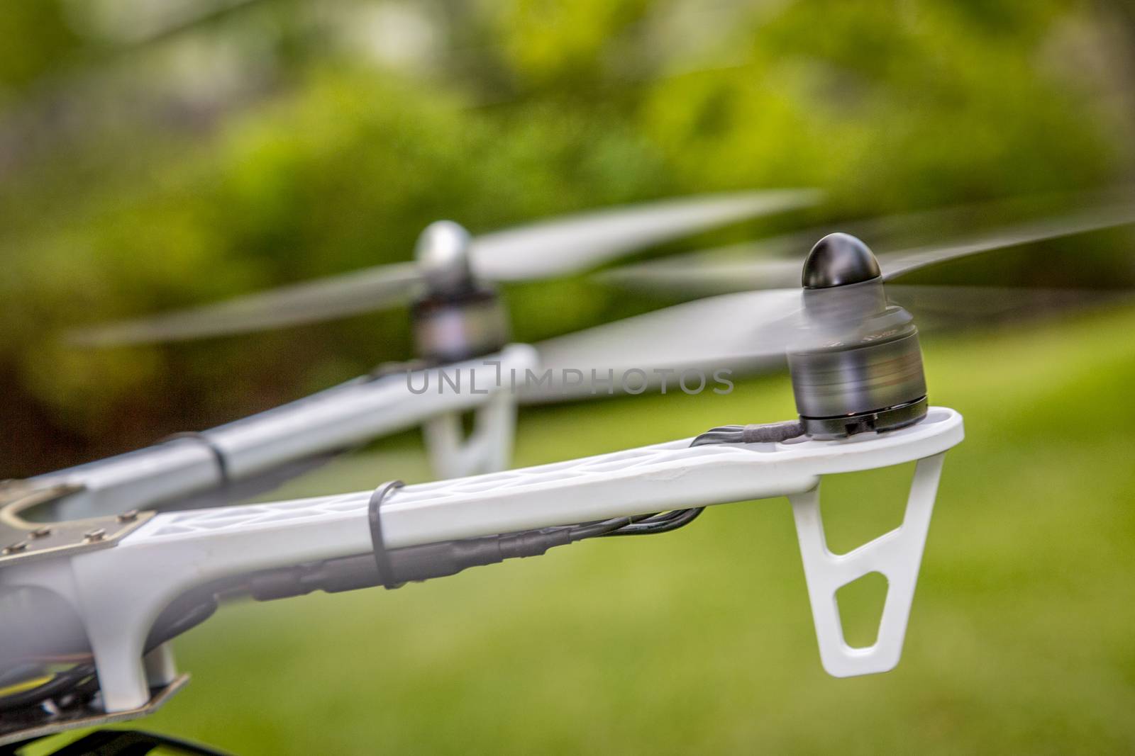 blurred spinning propellers of a hexacopter drone flying over green area