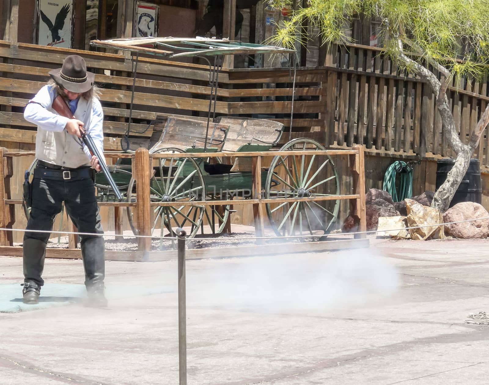 Calico, CA, USA - May 18, 2008: Cowboy (maybe sheriff) shooting with rifle at old carriage in Calico Ghost Town, abandoned and obsolete silver mining town in the Mojave desert.