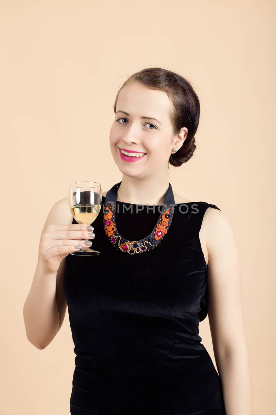 Studio portrait of smiling beautiful young brunette woman holding a glass of white wine