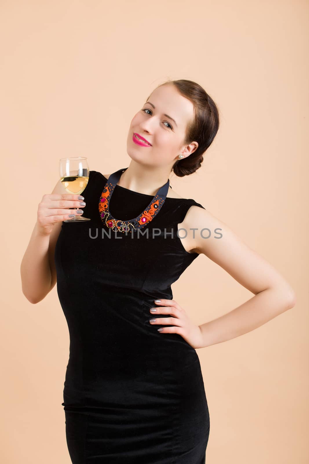 Studio portrait of smiling beautiful young brunette woman holding a glass of white wine