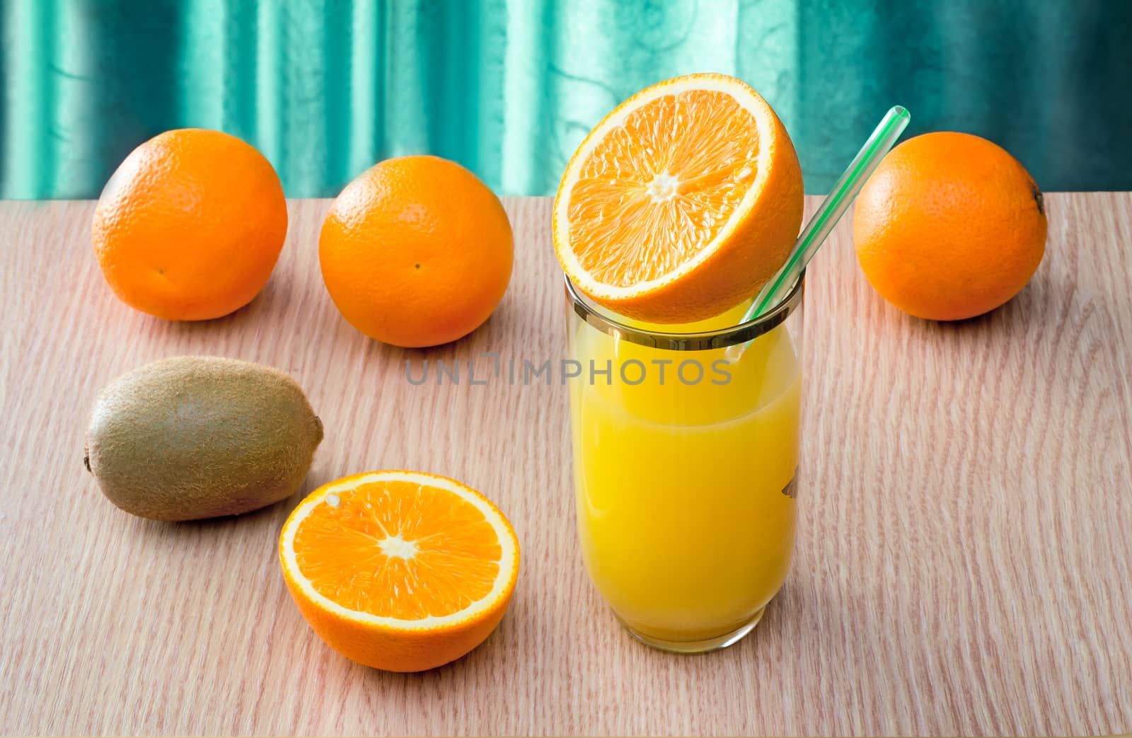 Fresh orange juice in the glass and some oranges on the table..