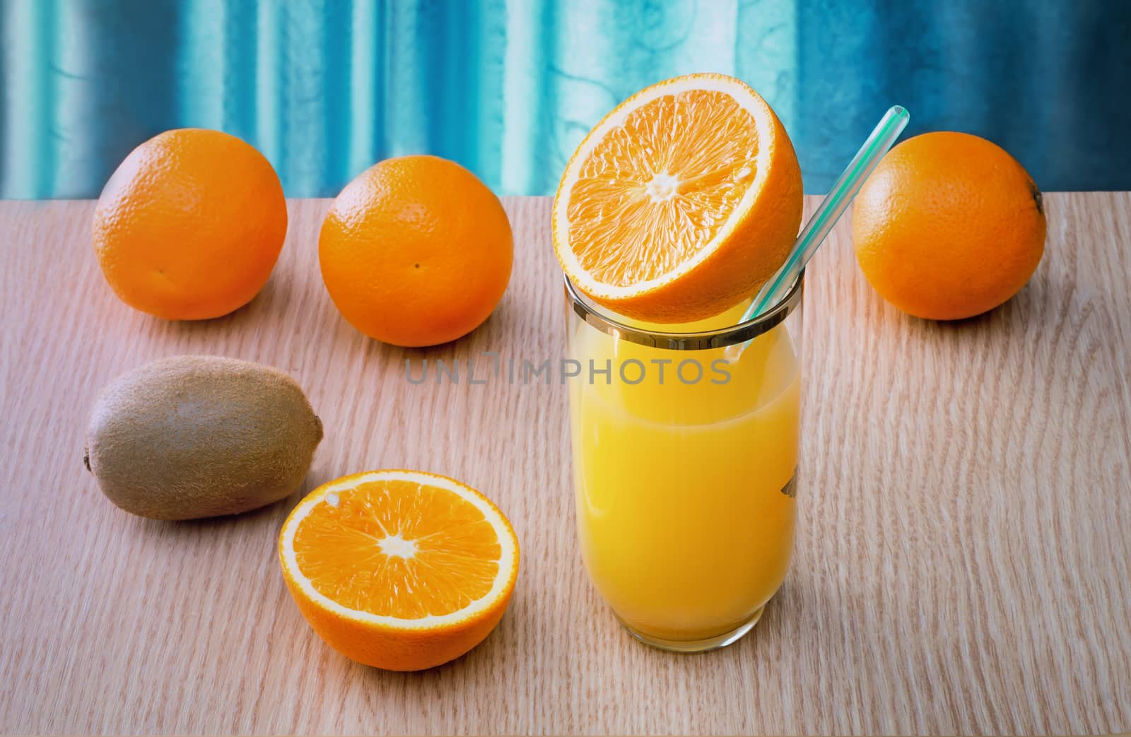 Fresh orange juice in the glass and some oranges on the table..