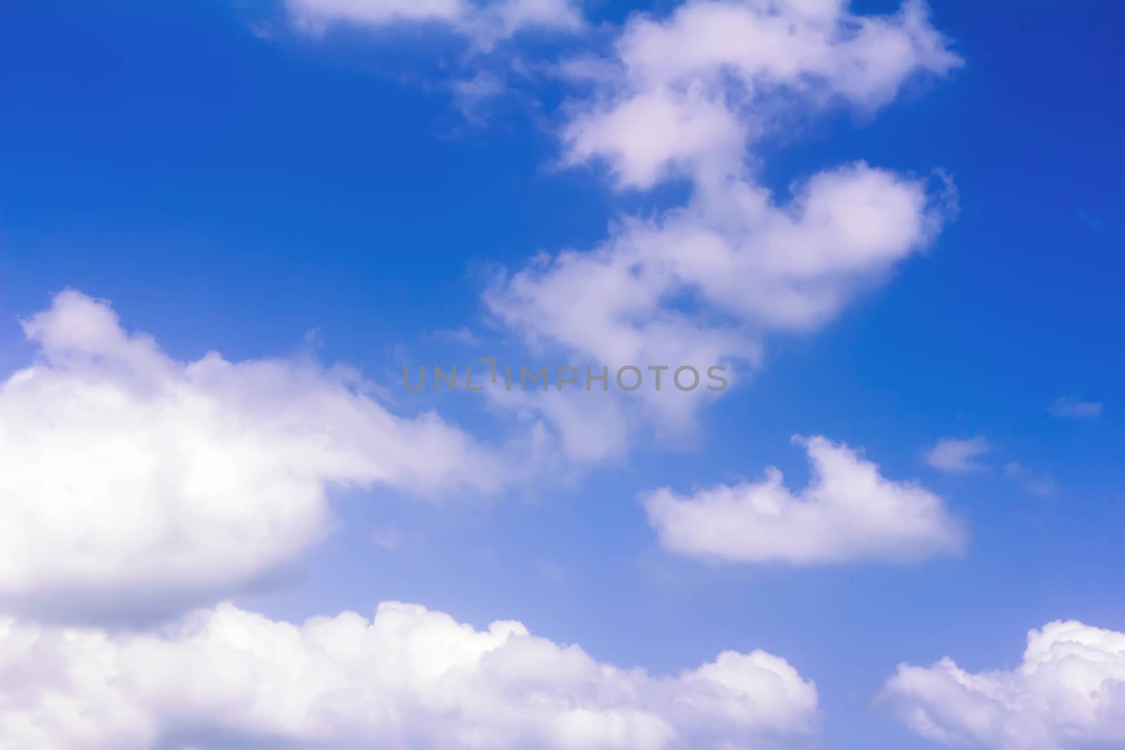 White fluffy clouds float on the blue sky in a clear sunny day.