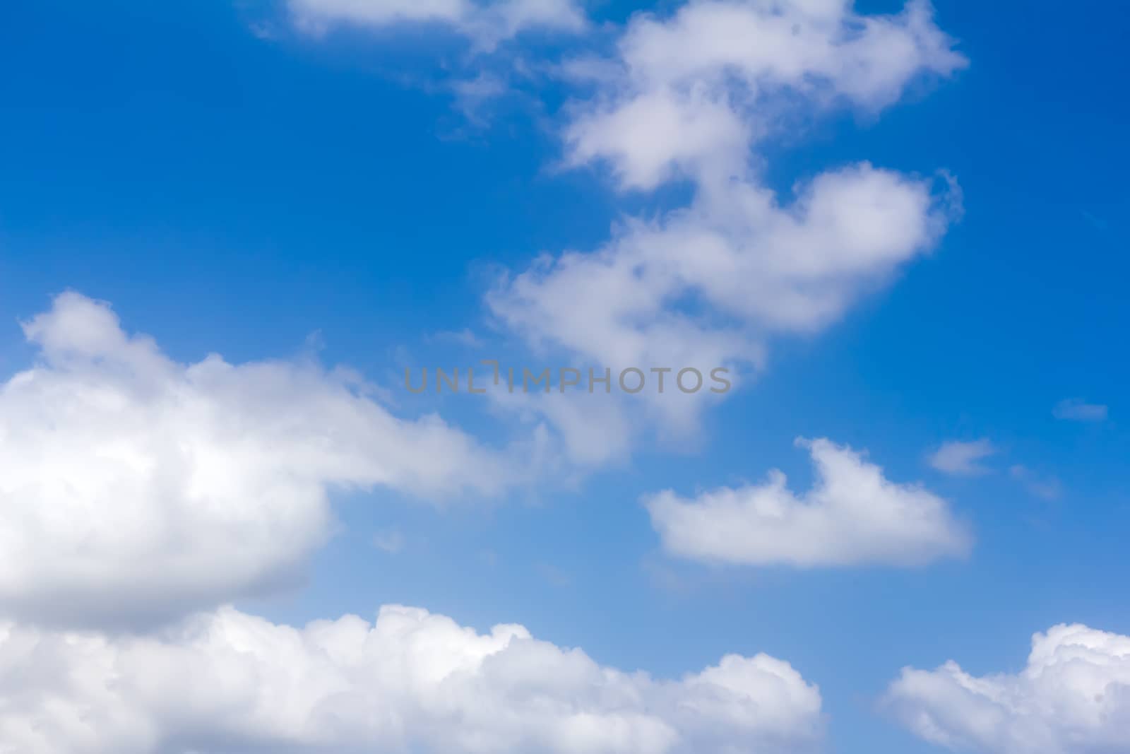 White fluffy clouds float on the blue sky in a clear sunny day.