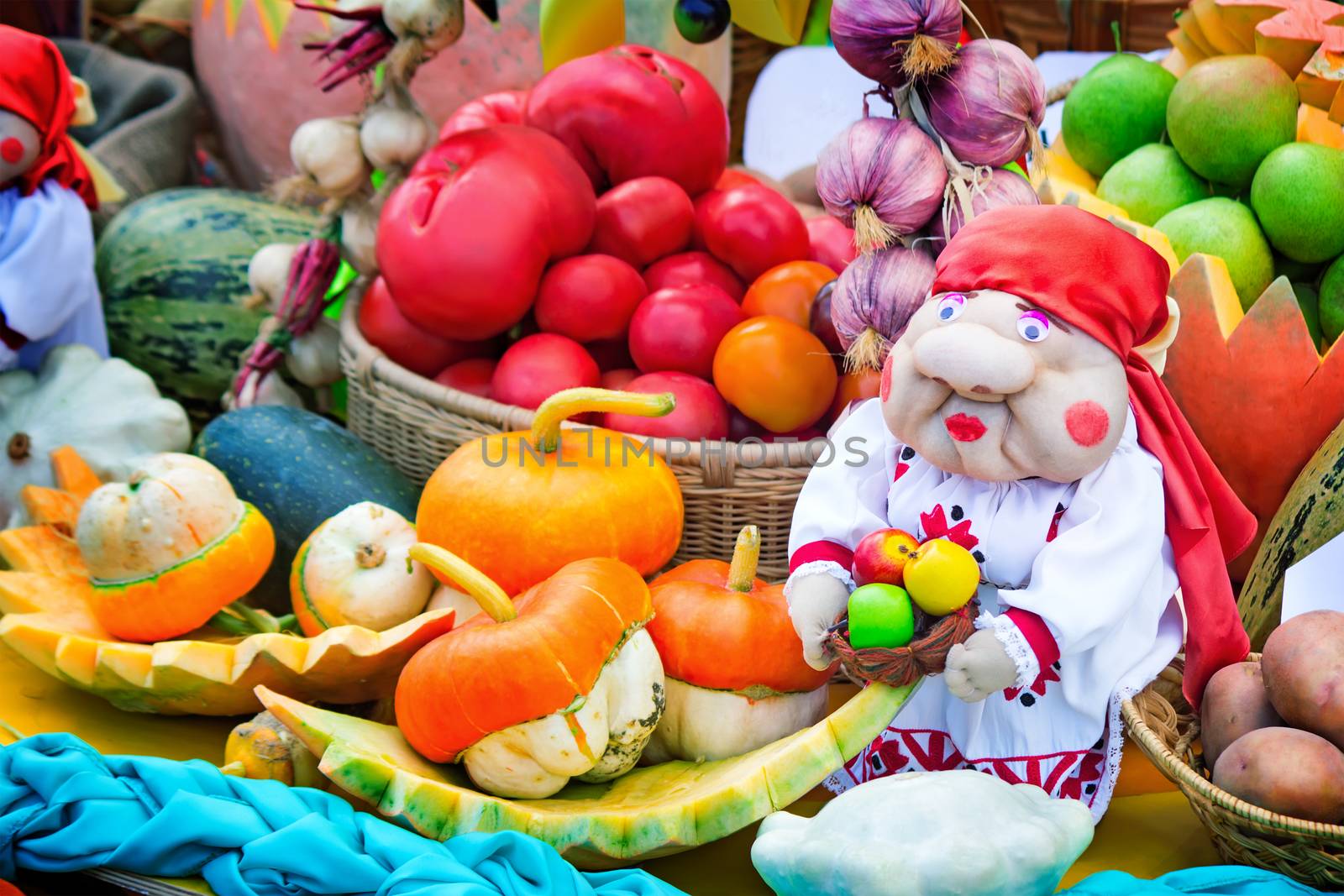 On display for sale at the fair are a variety of vegetables: pumpkin, onions, beets, zucchini , tomatoes, garlic. Next to it is a figure of fun women.