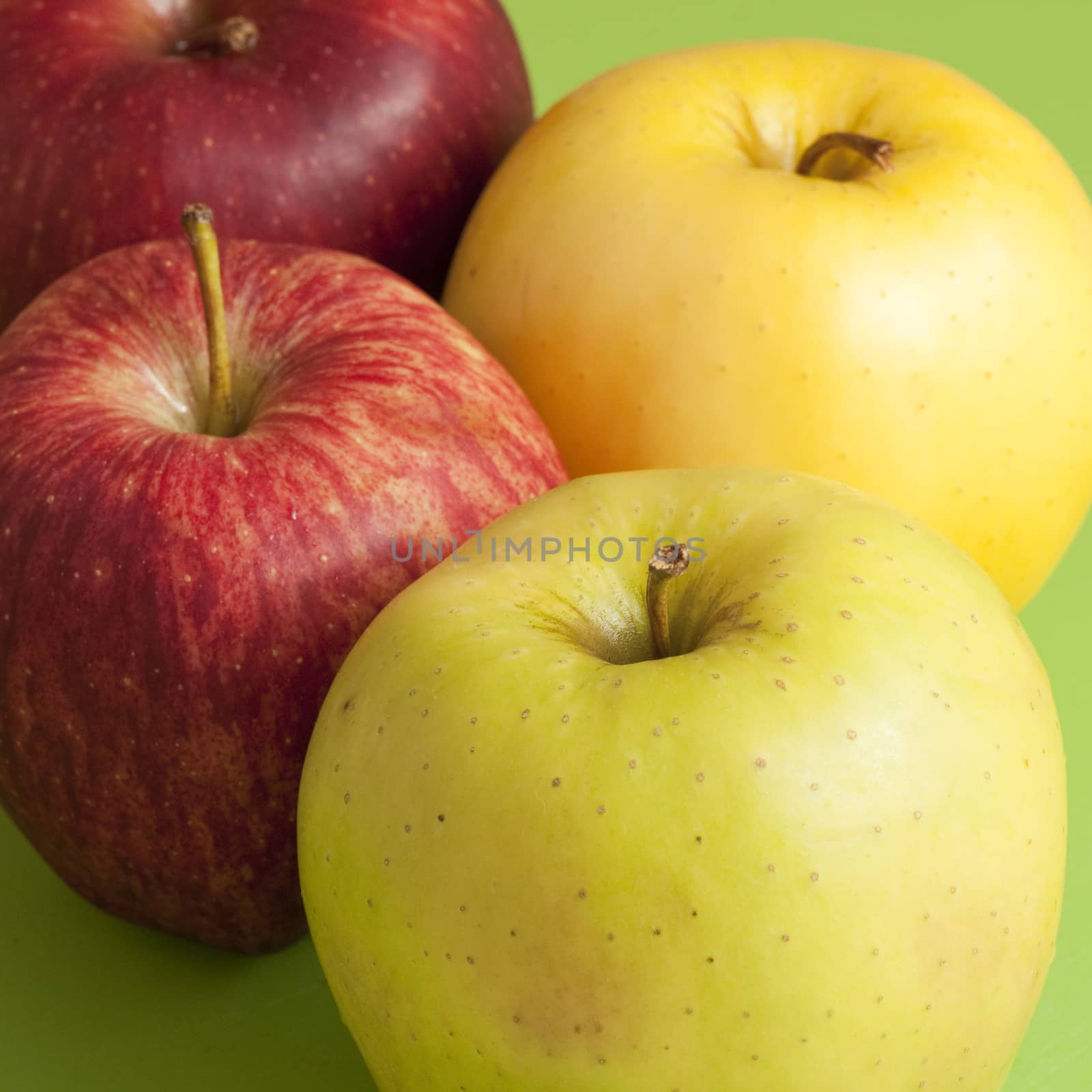 red and green apples on a green floor and a whole pear