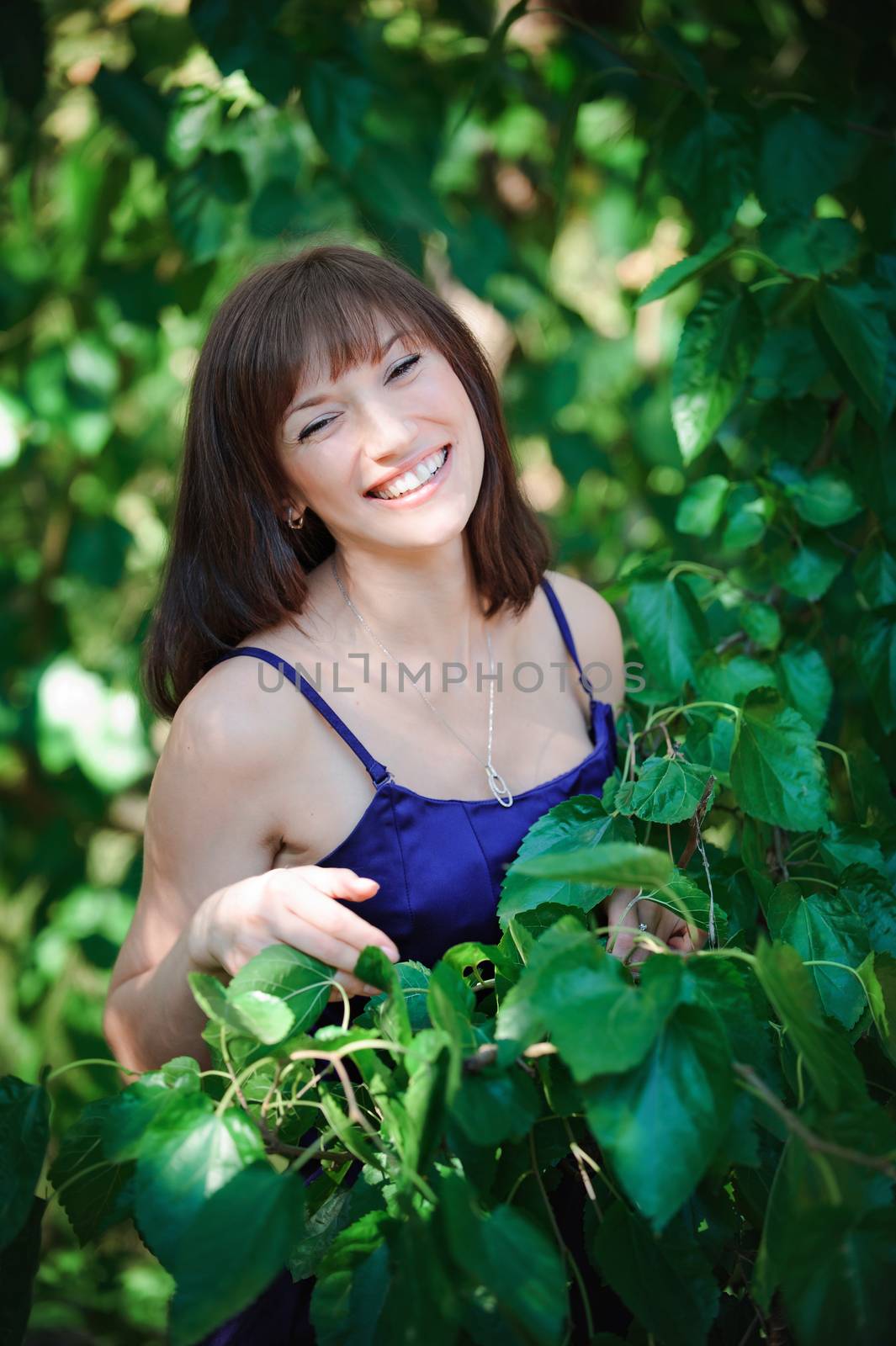 beautiful girl on a background of green leaves in summer park.