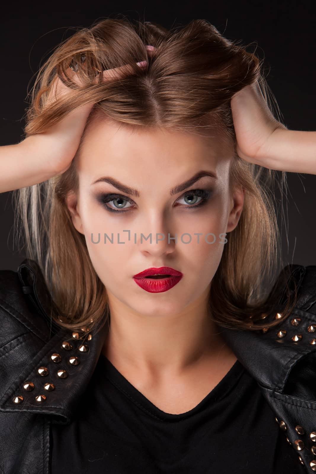 Close-up portrait of beautiful model with long blond hair on black background. hands in hair