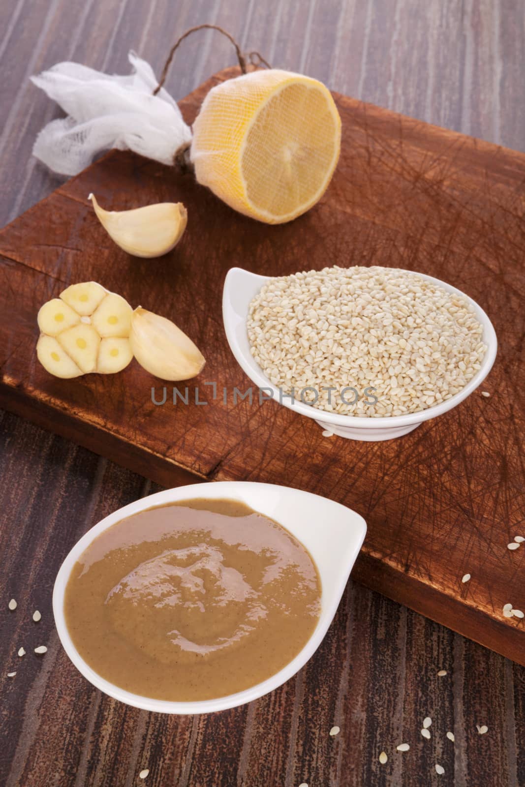 Tahini pasta, sesame seeds, lemon and garlic on brown background. Culinary eating. 