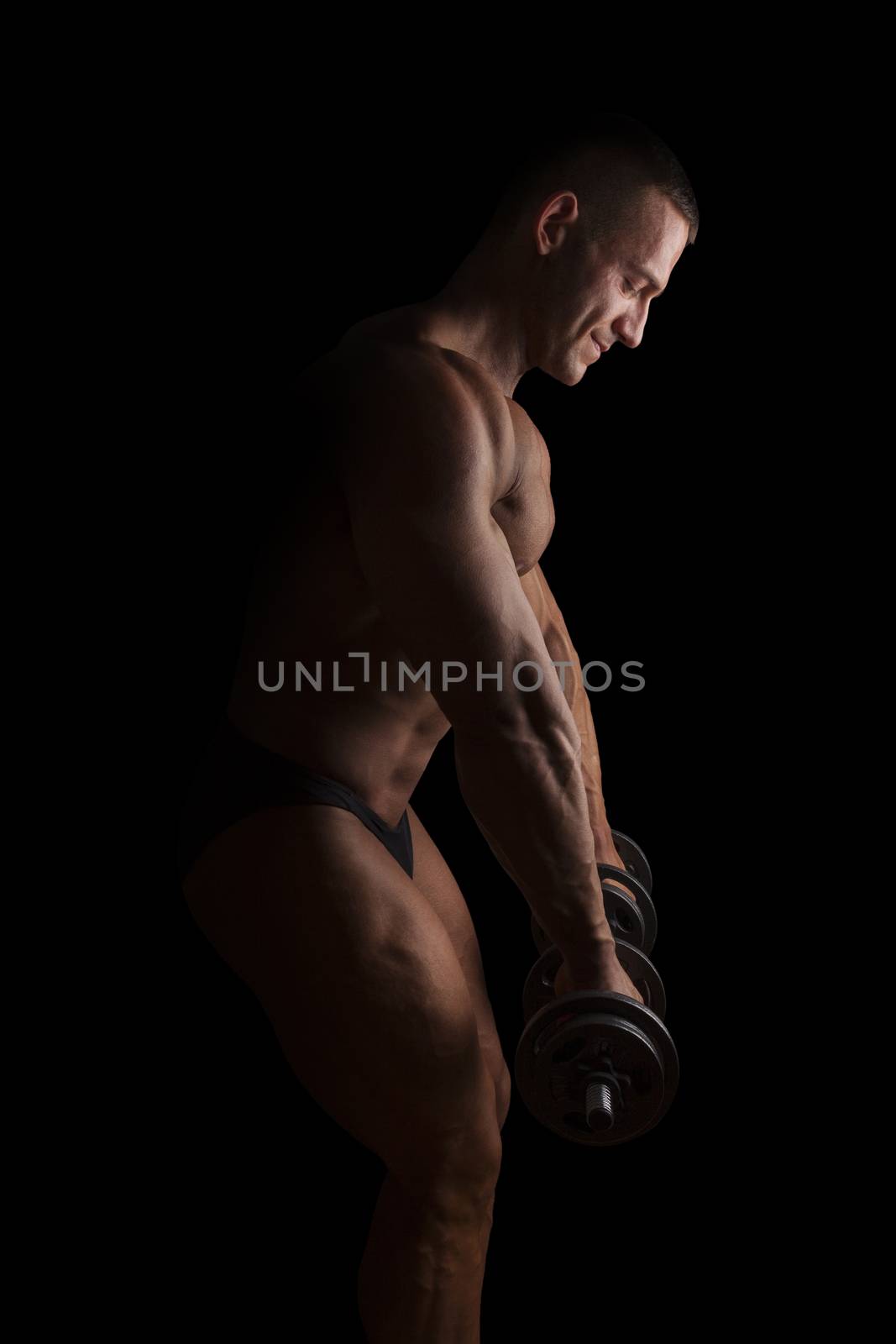 Sexy shirtless bodybuilder lifting weights isolated on black background. Extreme strength, muscles and fitness.