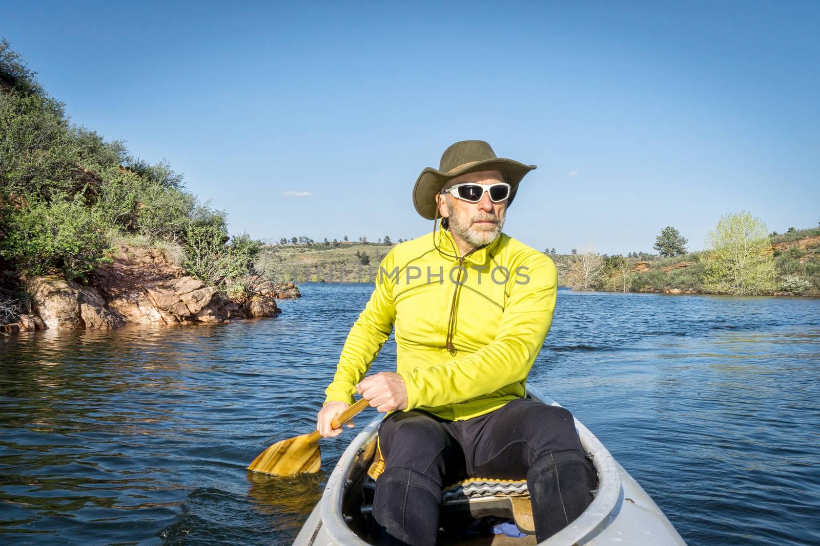 senior male paddling canoe by PixelsAway