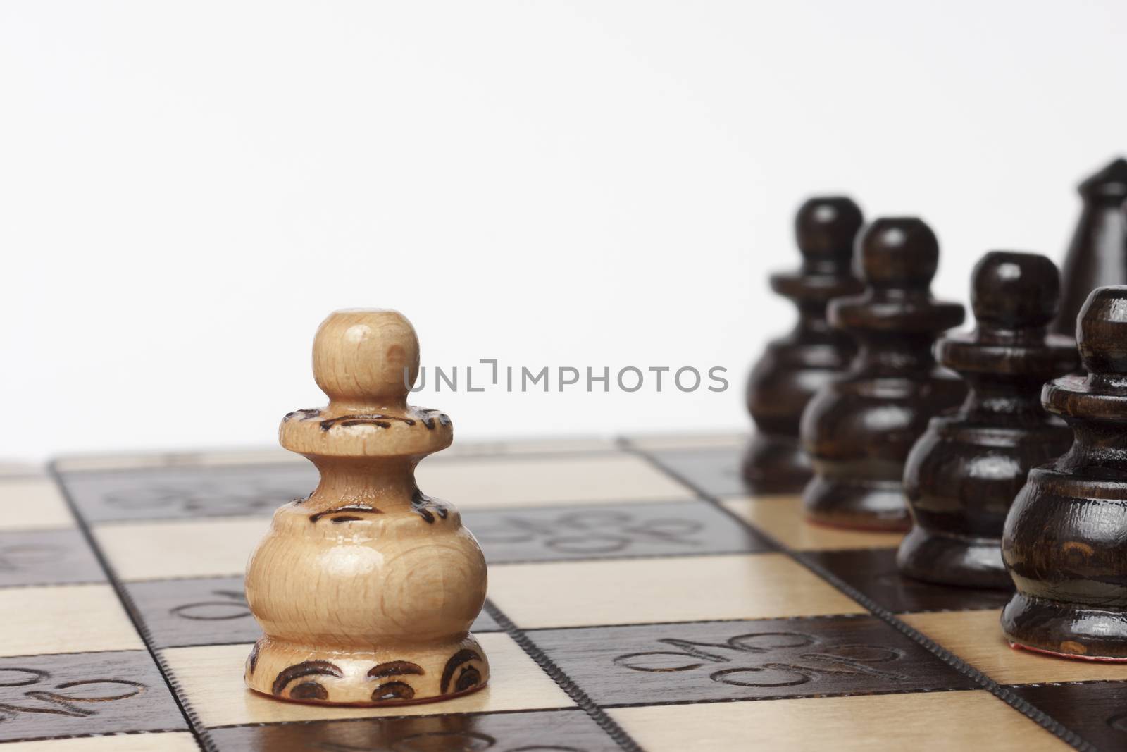 White pawn challenging army of black chess pieces selective focus