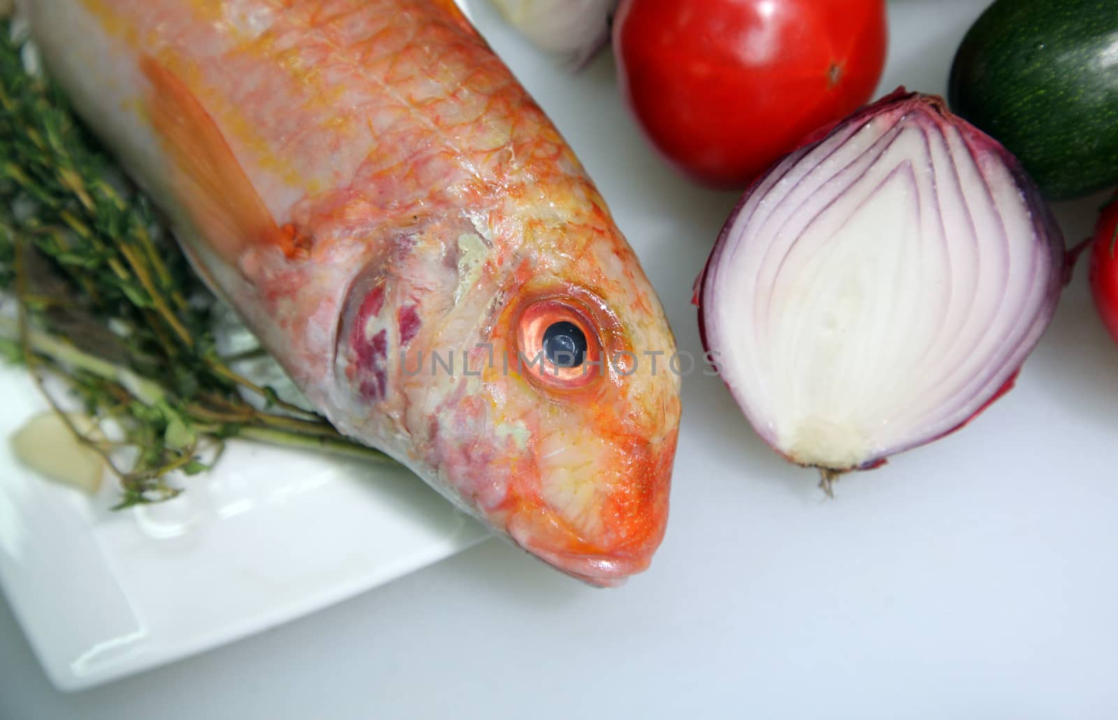 Red mullet with onion and vegetables. Close-up.