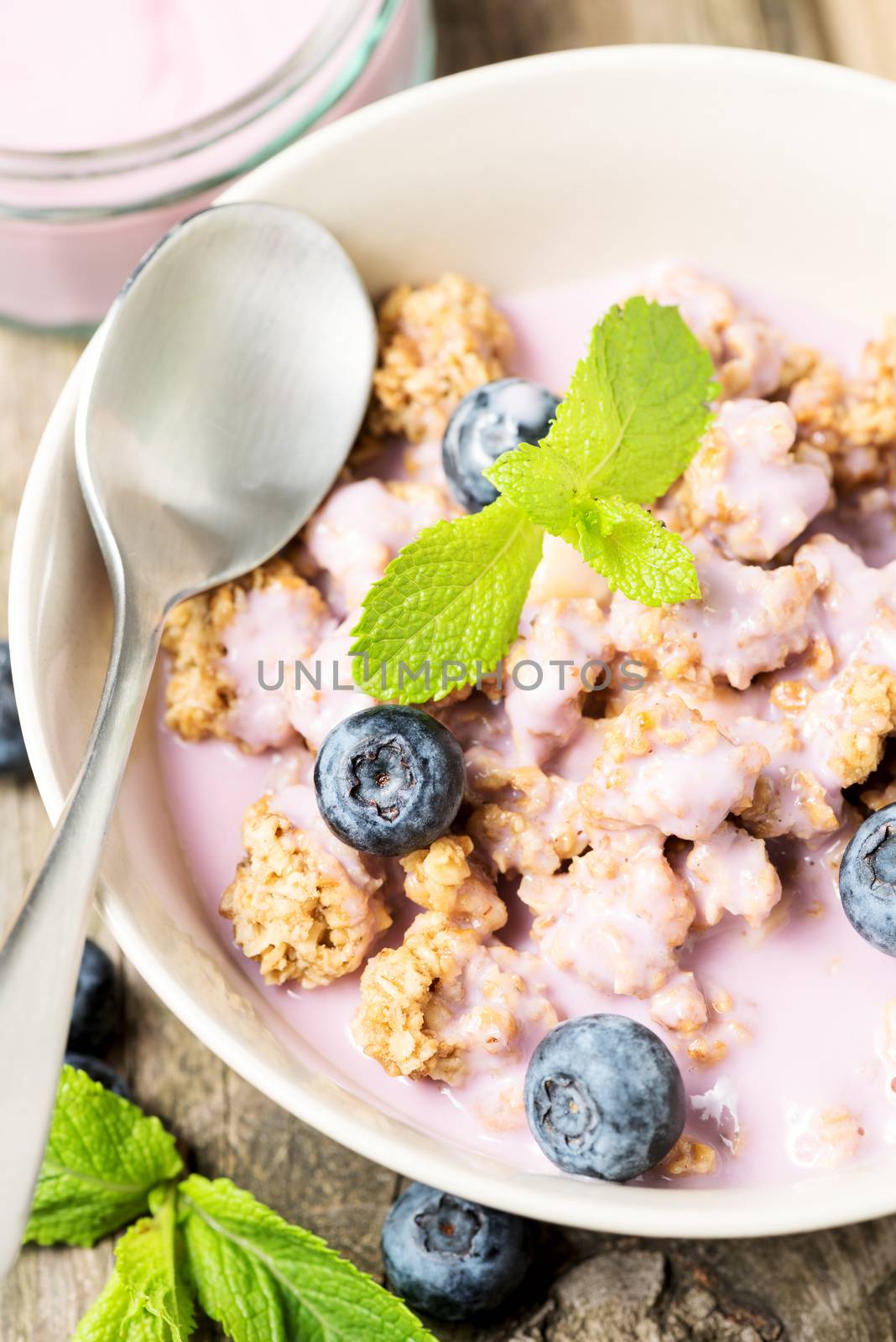 Fresh blueberry yogurt with granola and mint on a background