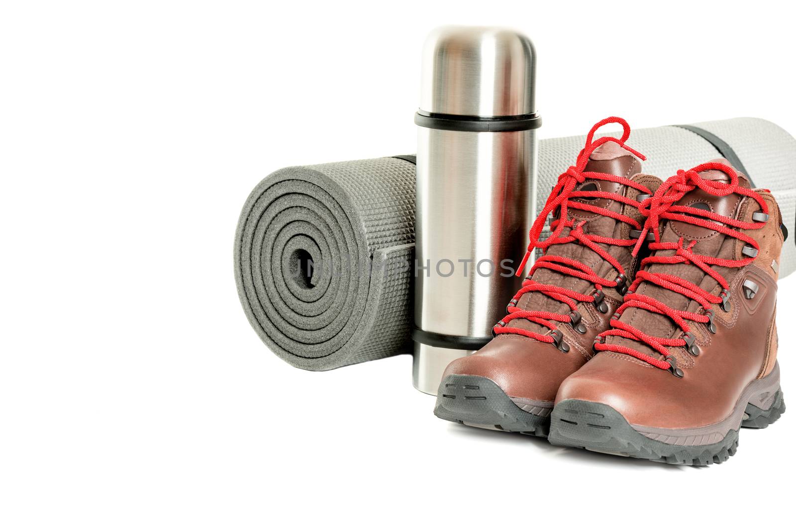 Hiker equipment: pair of mountain boots, thermo flask and sleeping mat on white background