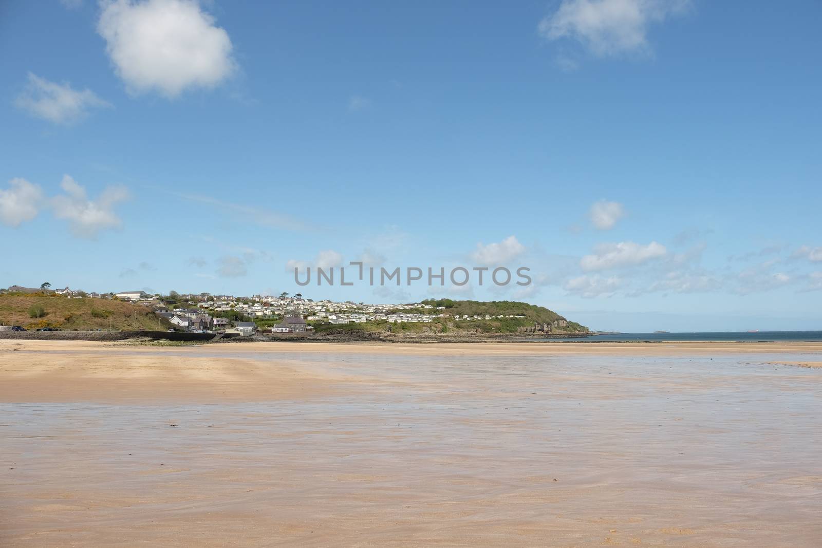 A view across the deserted clean sandy beach to the holiday village of Benllech, Anglesey, Wales, UK.