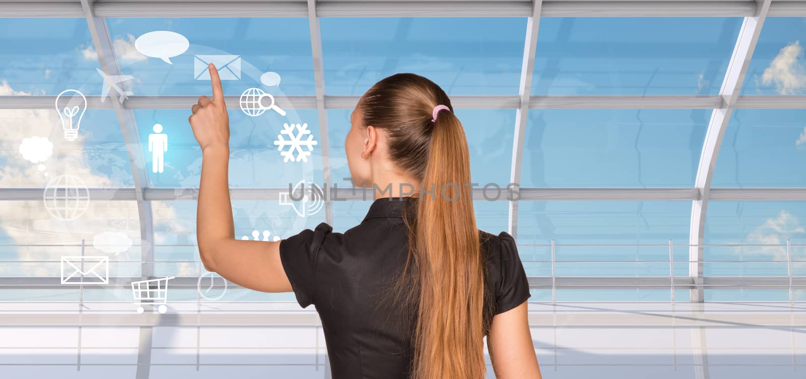 Rear view of businesswoman in dress pressing on holographic screen with icons