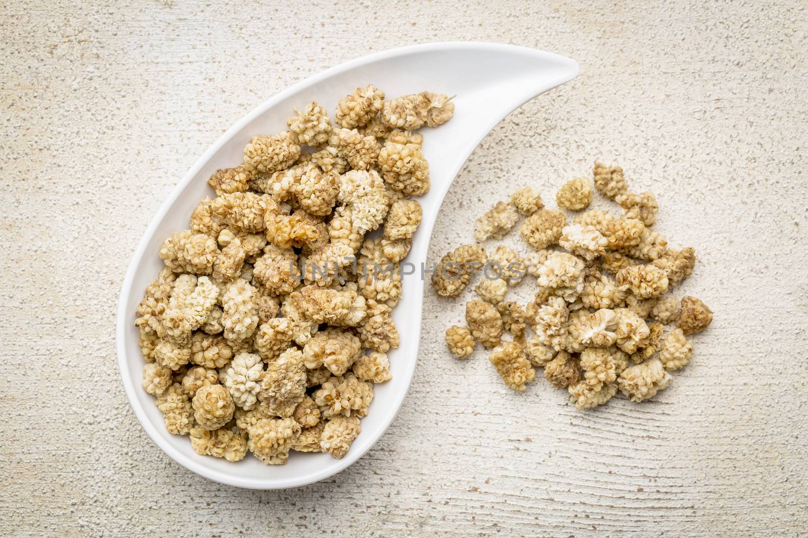 dried white mulberry on a teardrop shaped bowl against rustic barn wood