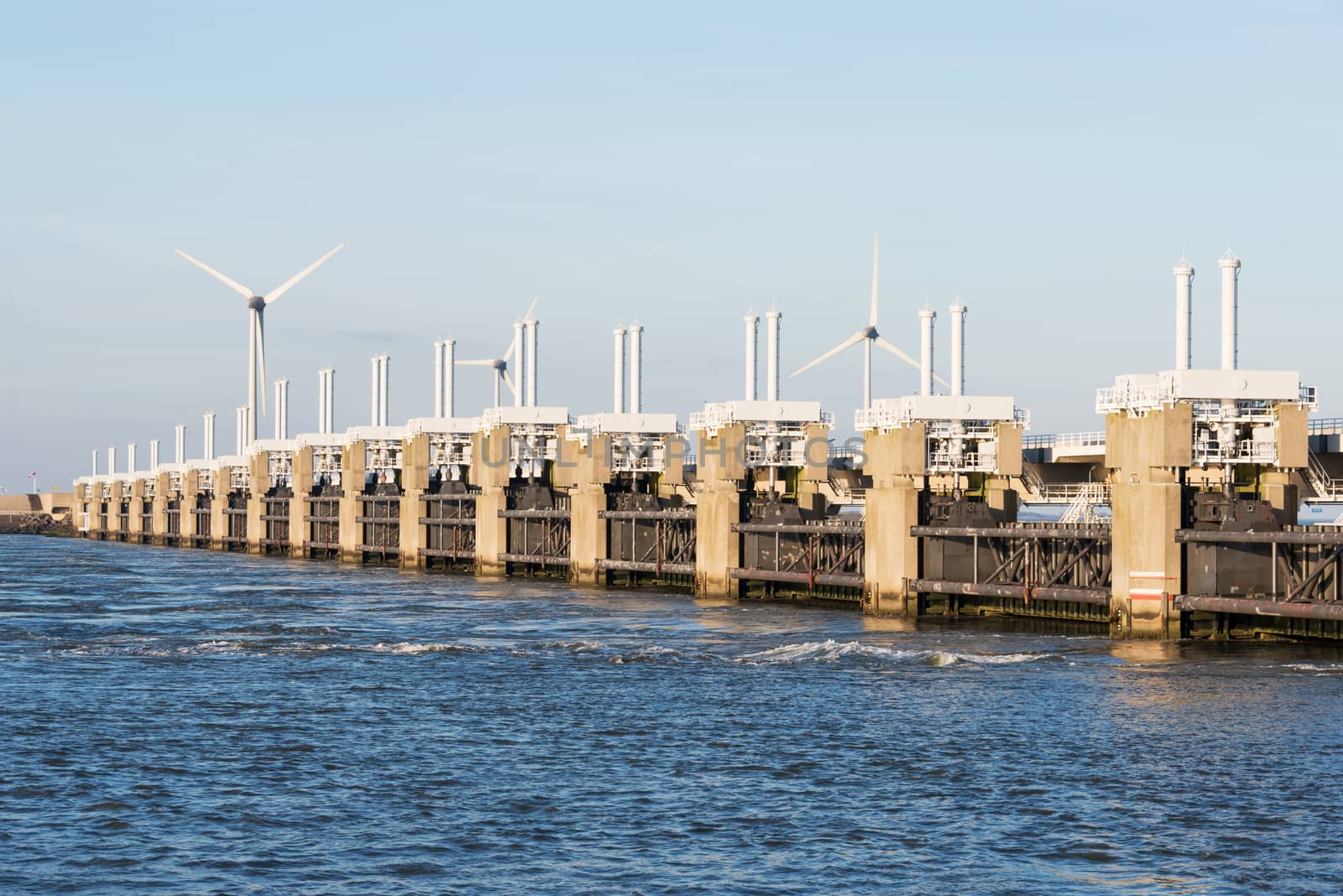 a deltaworks in holland at the Oosterschelde river to protect holland form high sea level, this is near the dutch museum neeltje jans with windmills as background