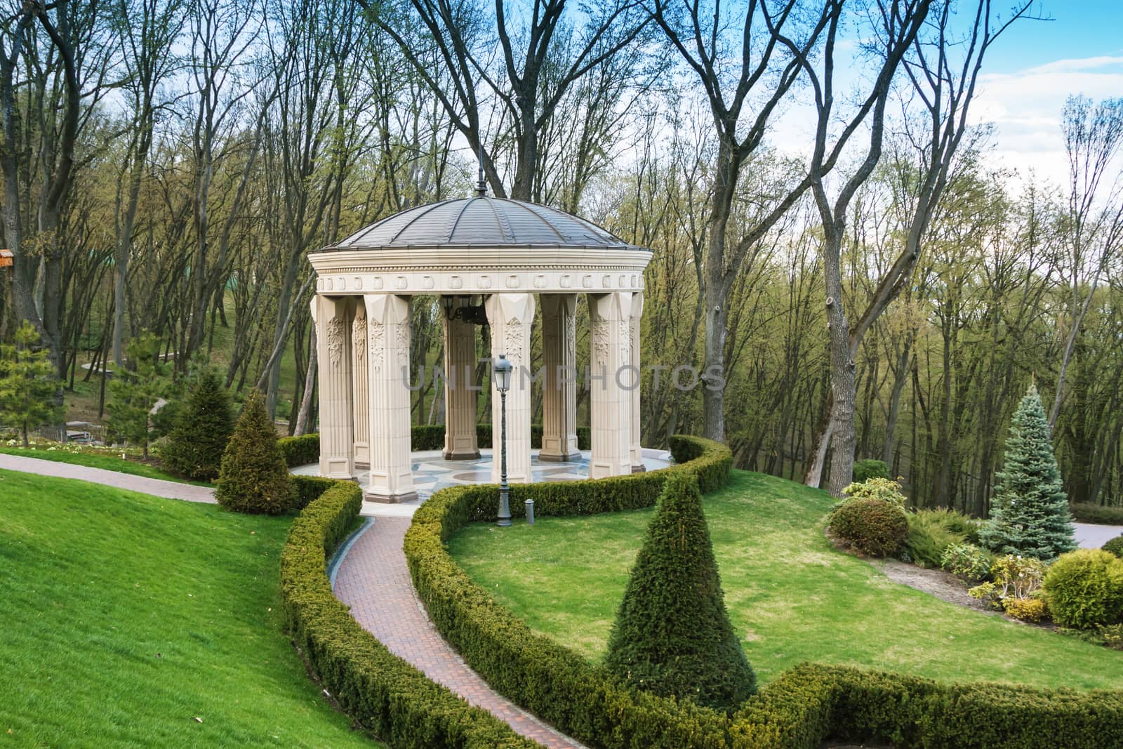 beautiful antic marble arbor in green summer garden