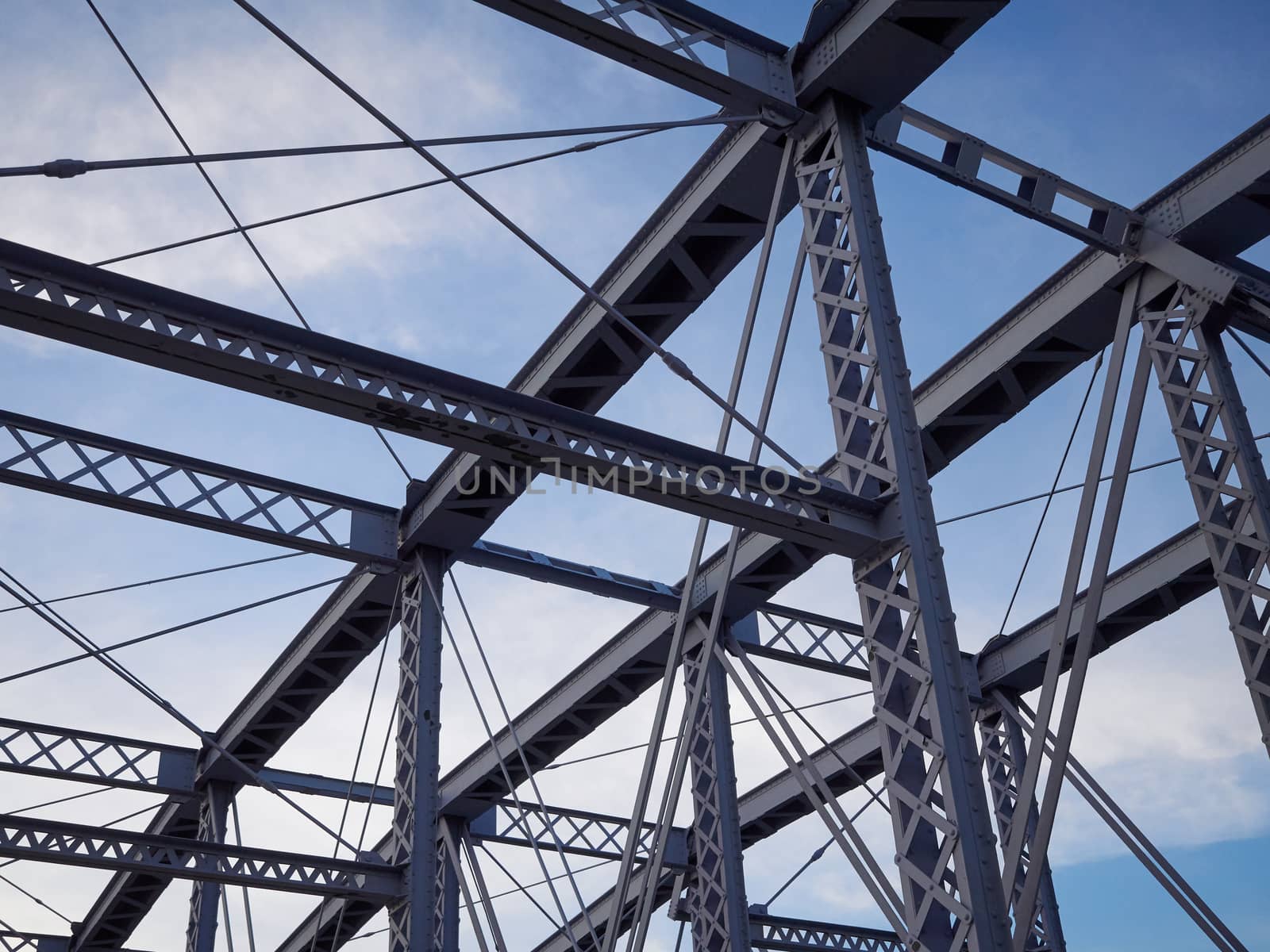 Detail shot of an historic gray painted Dutch riveted truss bridge against a blue sky.