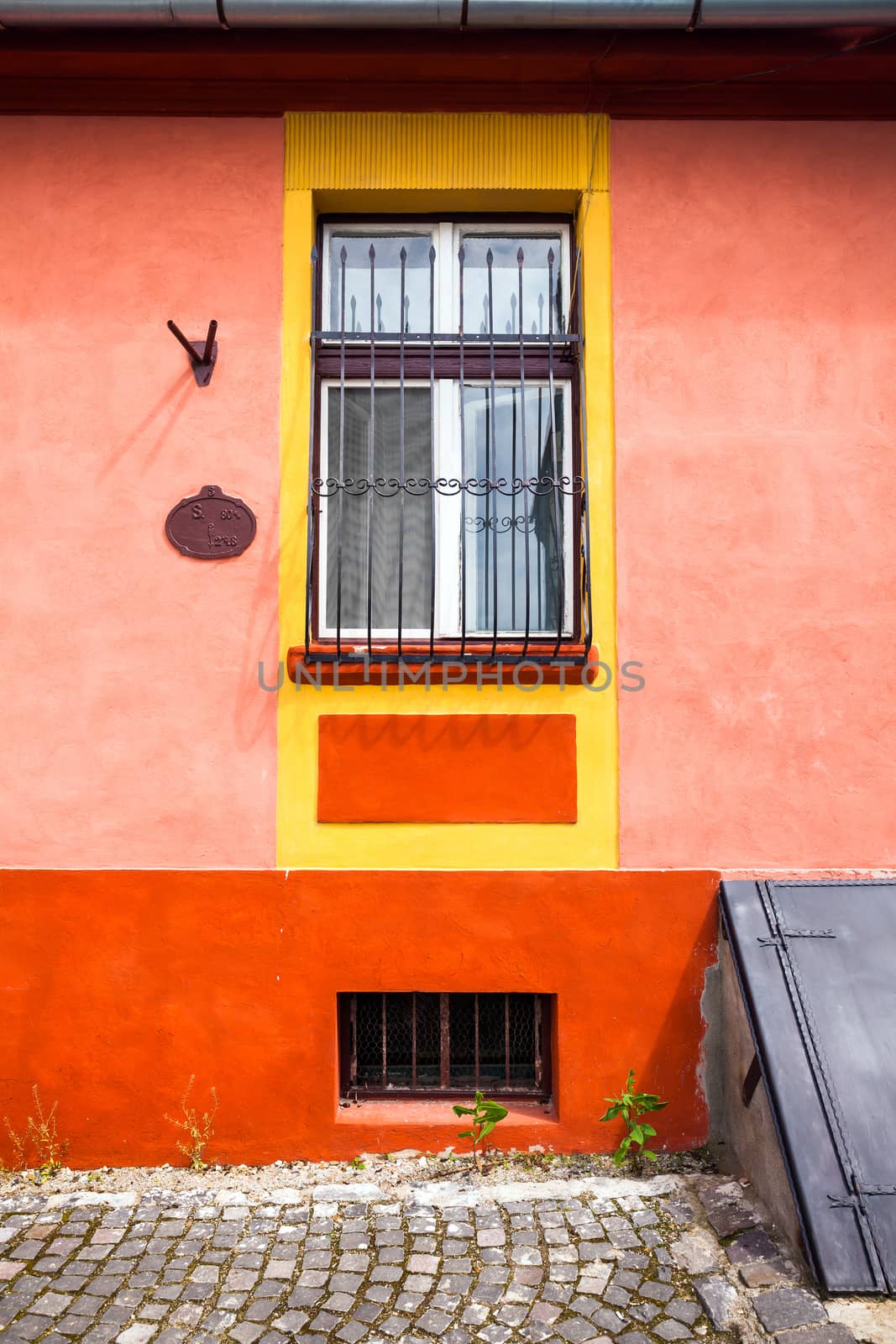 Sighisoara, Romania - June 23, 2013: Orange house facade with wooden window from Sighisoara city old center, Transylvania, Romania