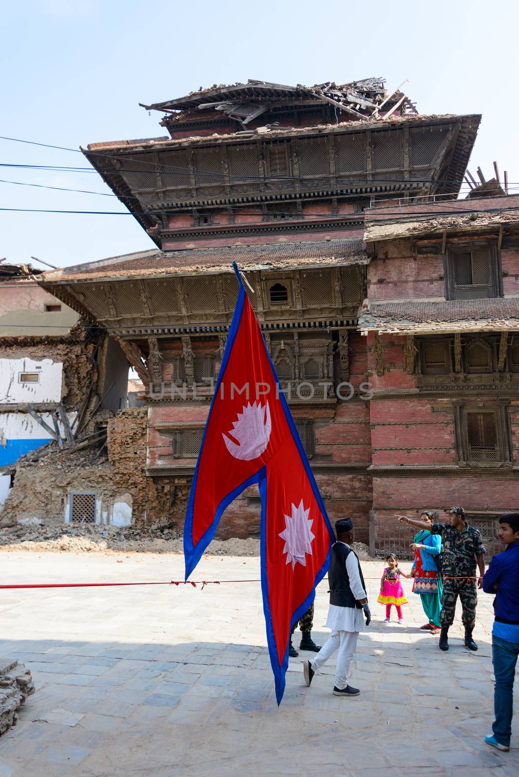 KATHMANDU, NEPAL - MAY 14, 2015: A man carries a large Nepal flag on Durbar Square, a UNESCO World Heritage Site.