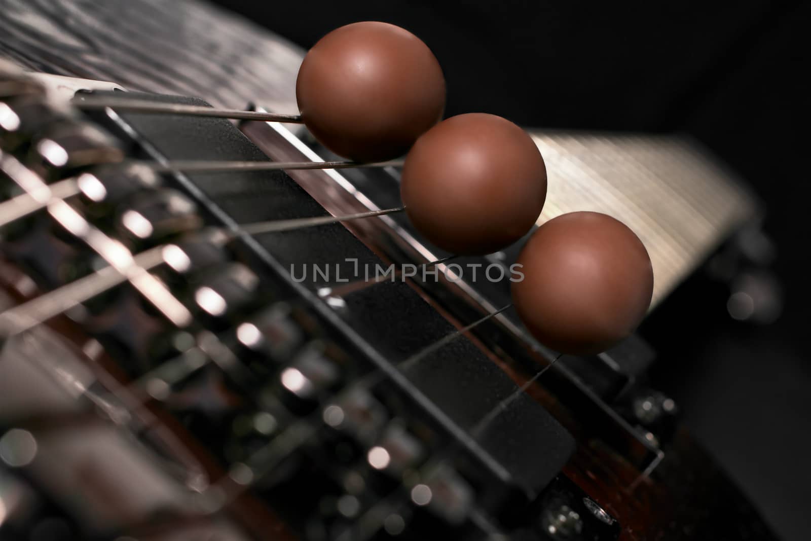 three chocolate eggs placed on the strings of a guitar