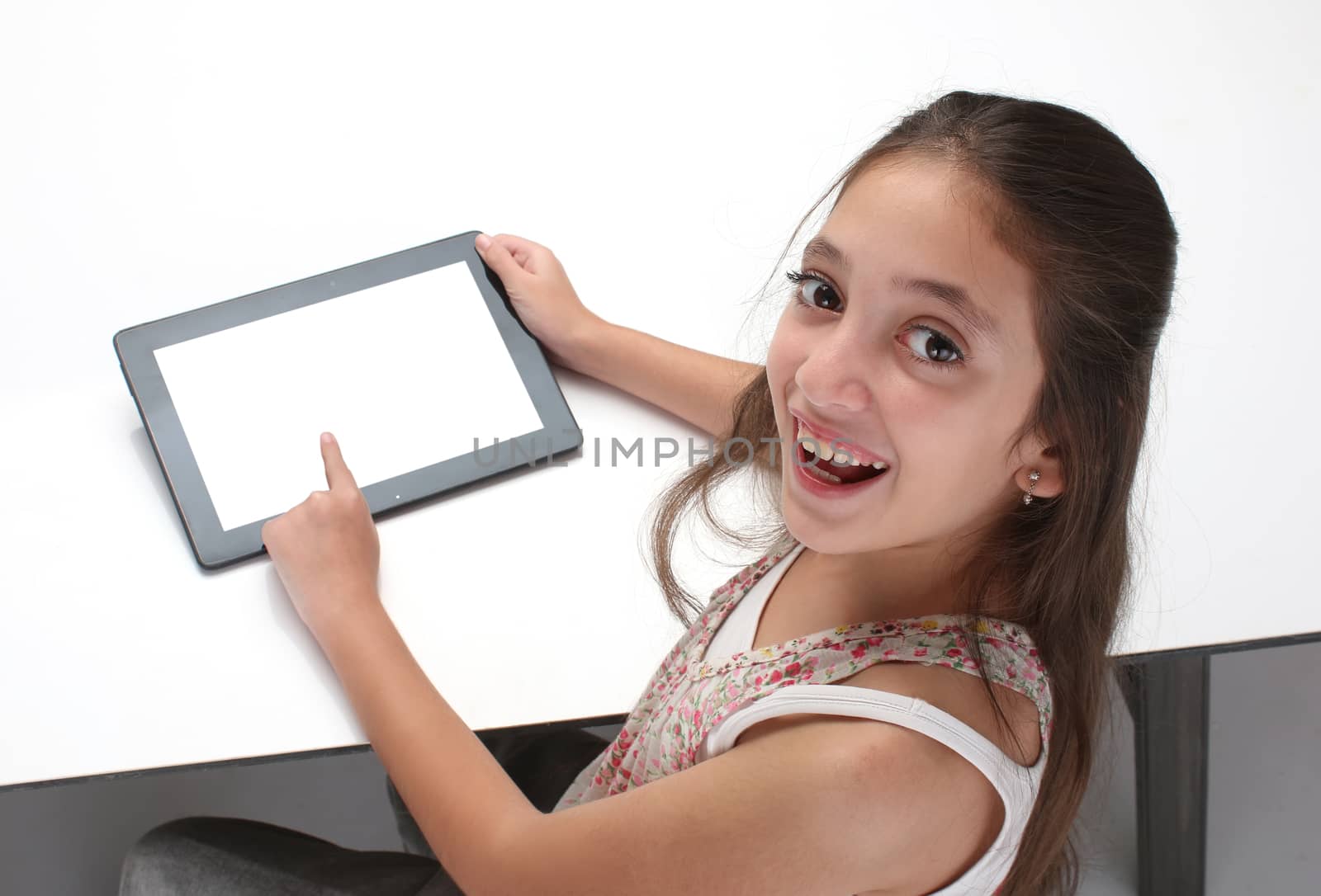 Beaitiful pre-teen girl using a tablet computer. High angle. Clipping path for the screen