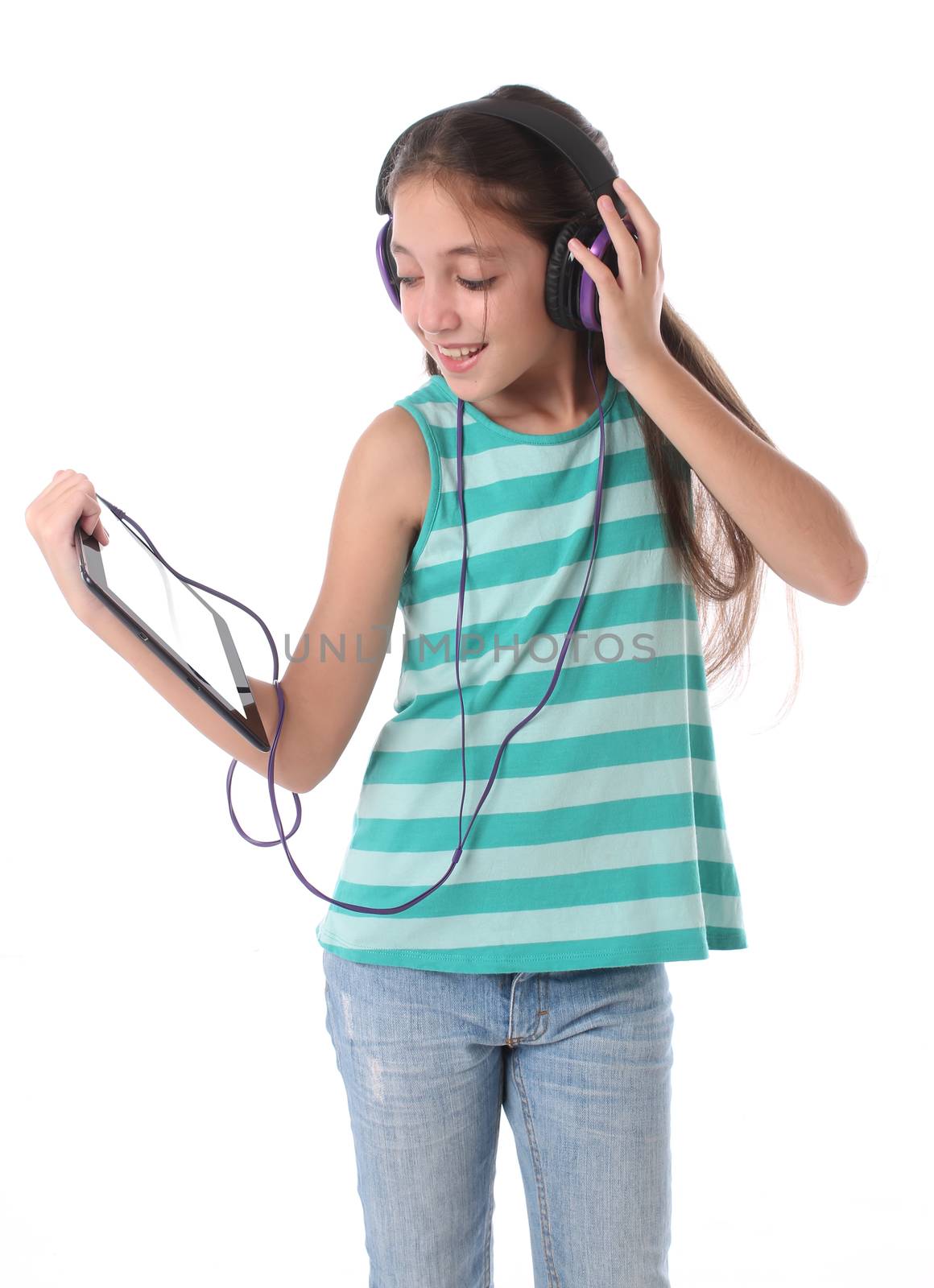 Beautiful pre-teen girl using a tablet computer and headphones. by Erdosain