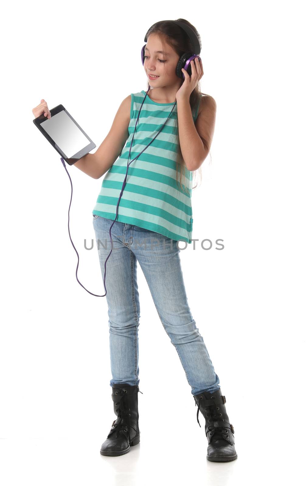 Beautiful pre-teen girl using a tablet computer and headphones. by Erdosain