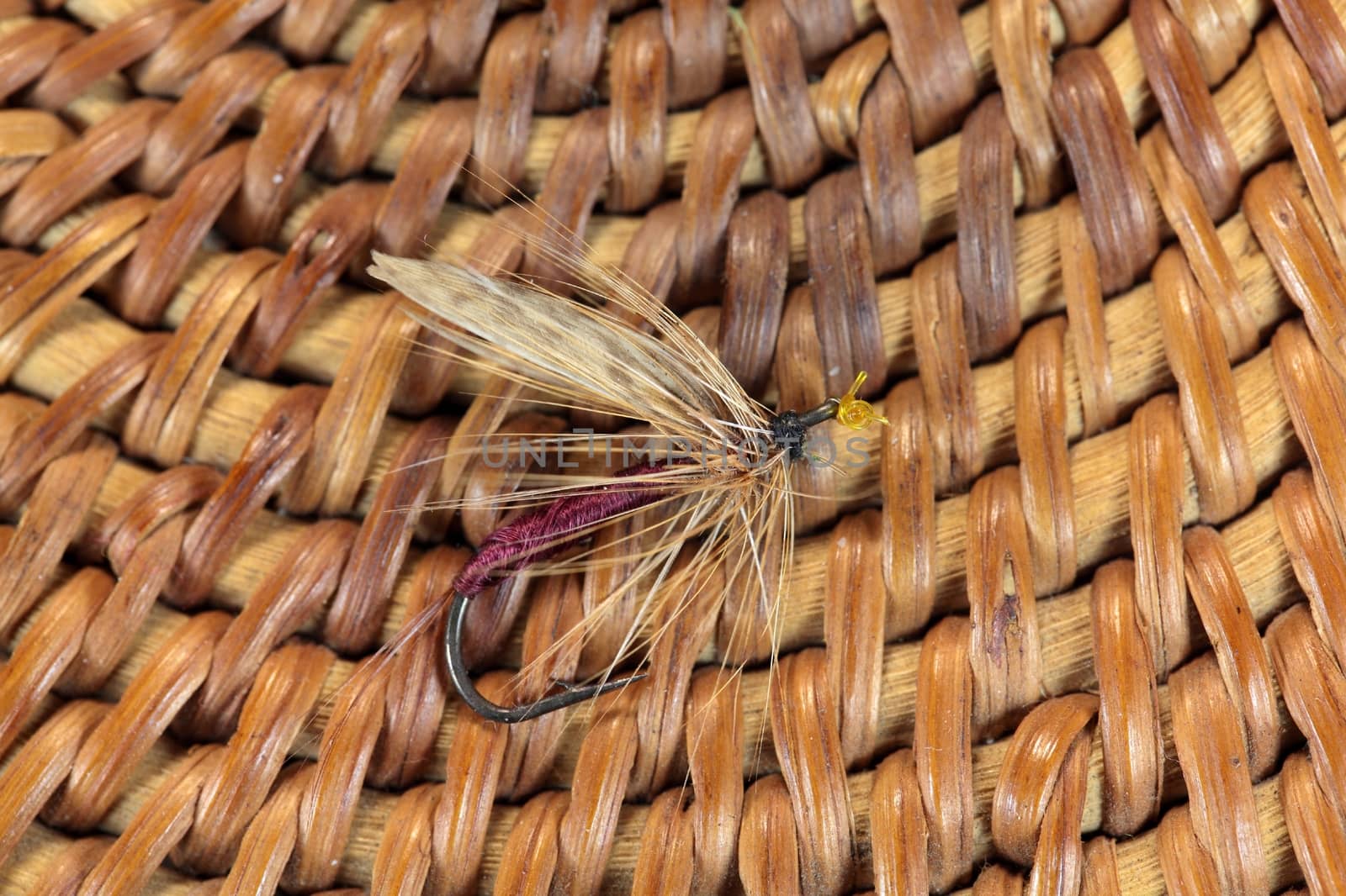 Macro photo of an artificial fly for fly fishing on a basketwork background.