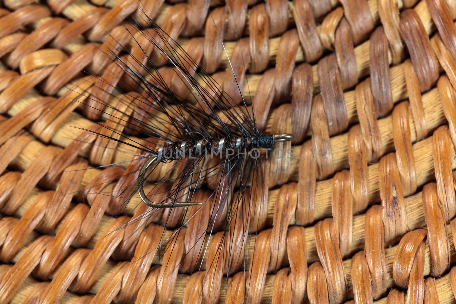 Macro photo of an artificial fly for fly fishing on a basketwork background.