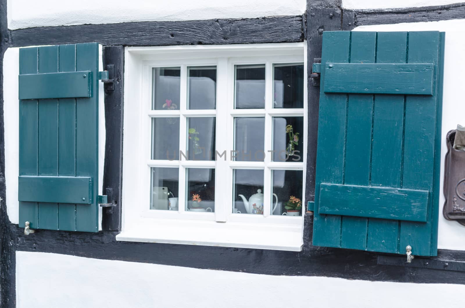 Shutters in front of a window of a half-timbered house with stopes.